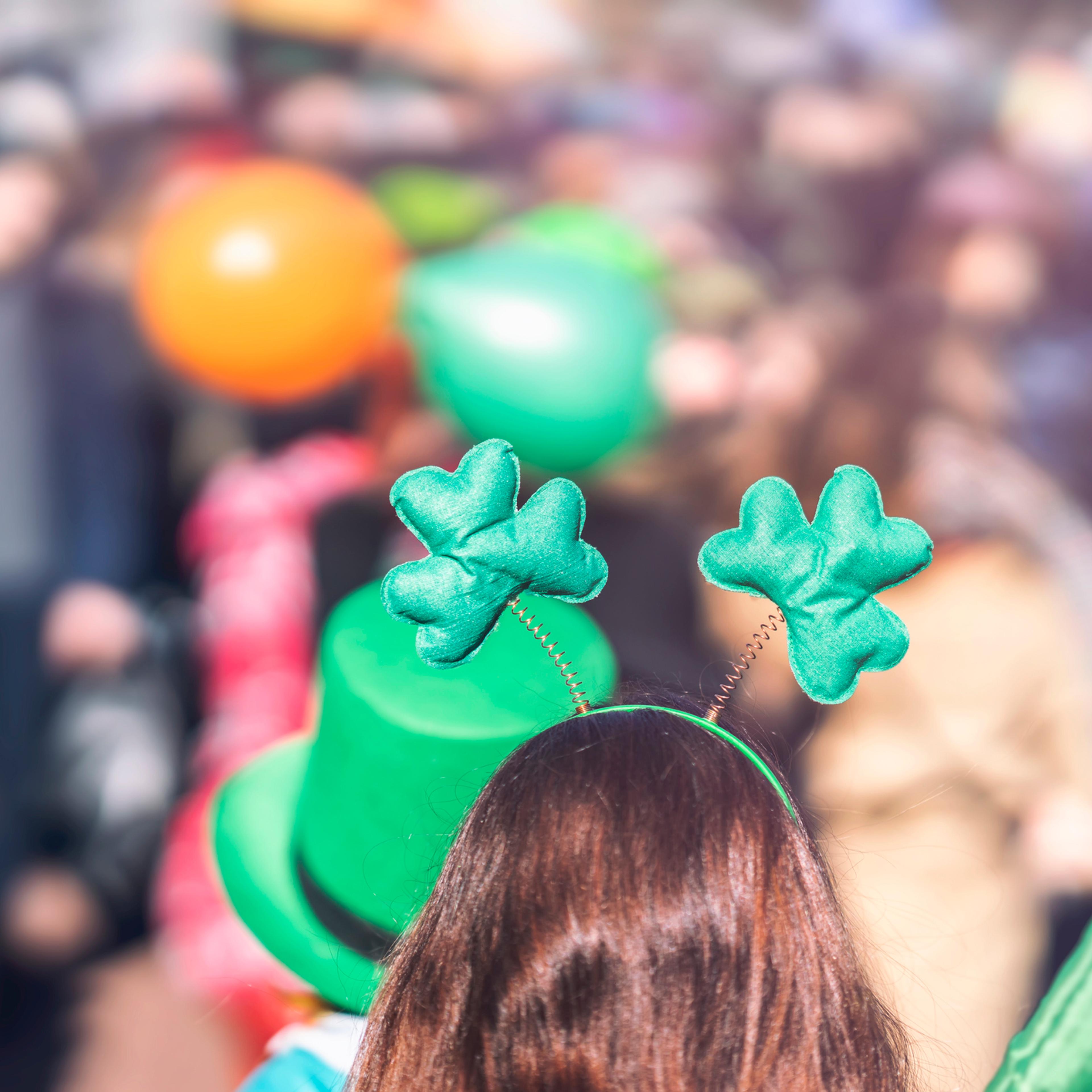 Clover head decoration on head of girl close-up. Saint Patrick day, parade in the city, selectriv focus