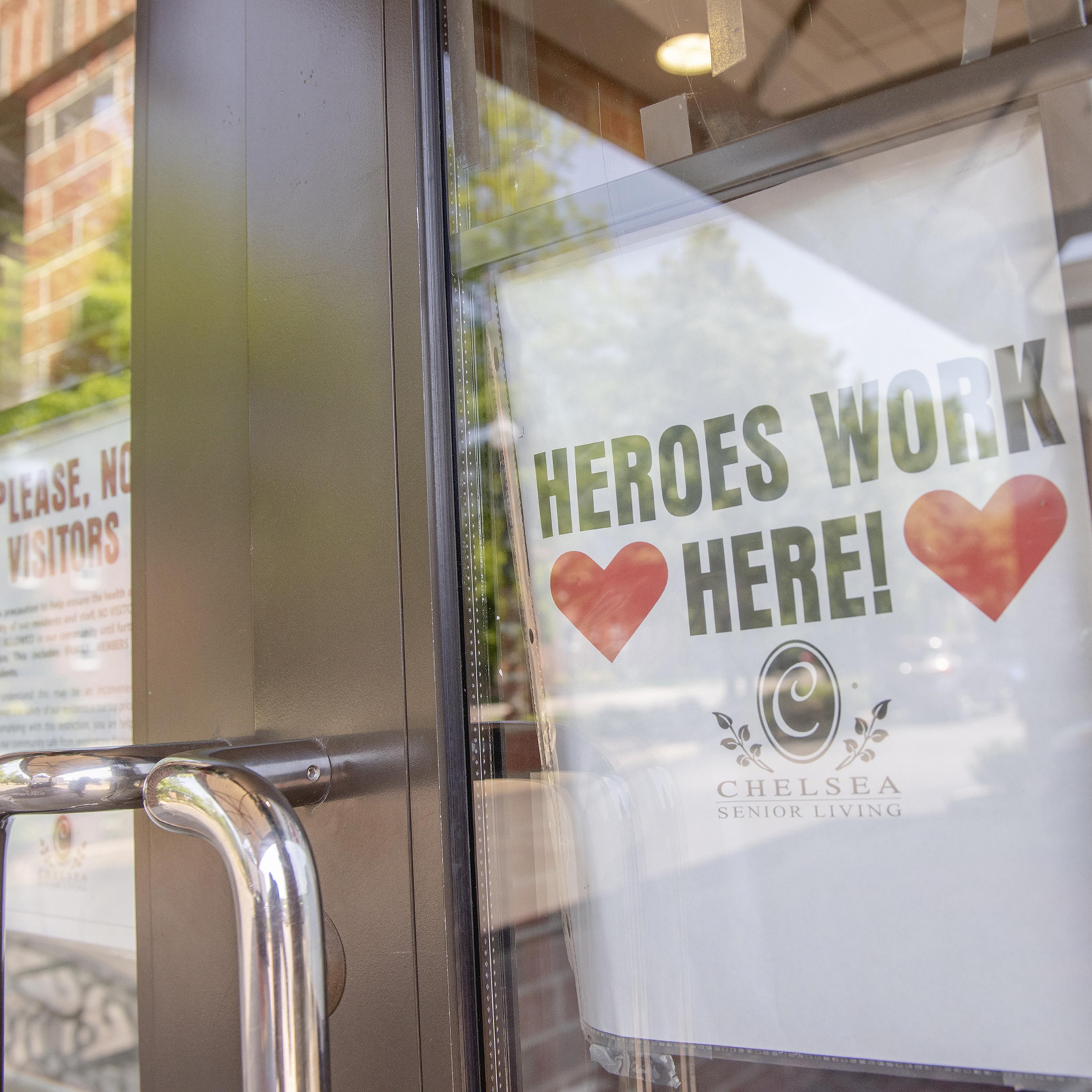 A sign reading "Heroes Work Here" is displayed in a window of the Maple Pointe Assisted Living facility in Rockville Centre, New York, on June 9