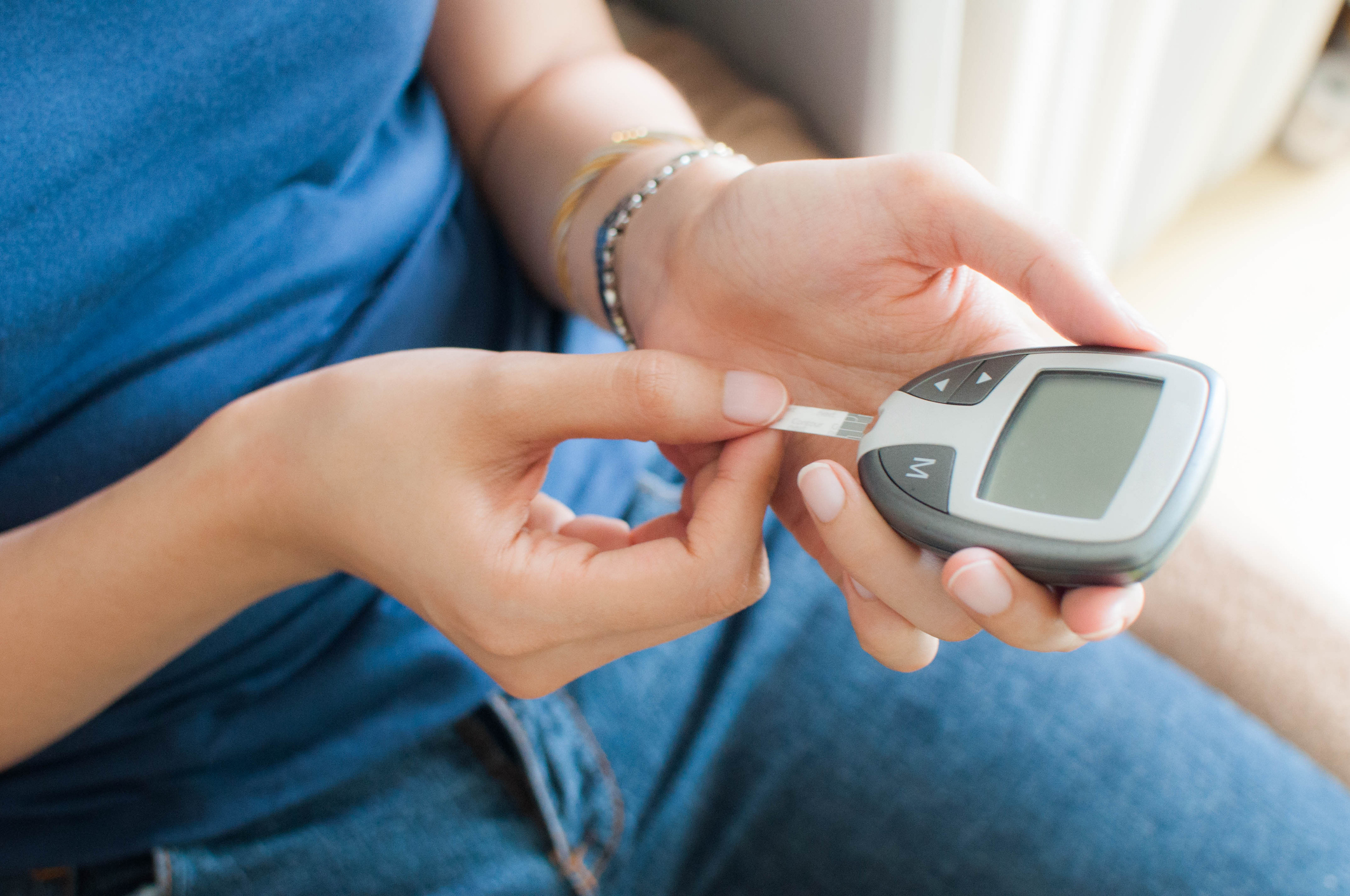 A young woman is using a glucometer