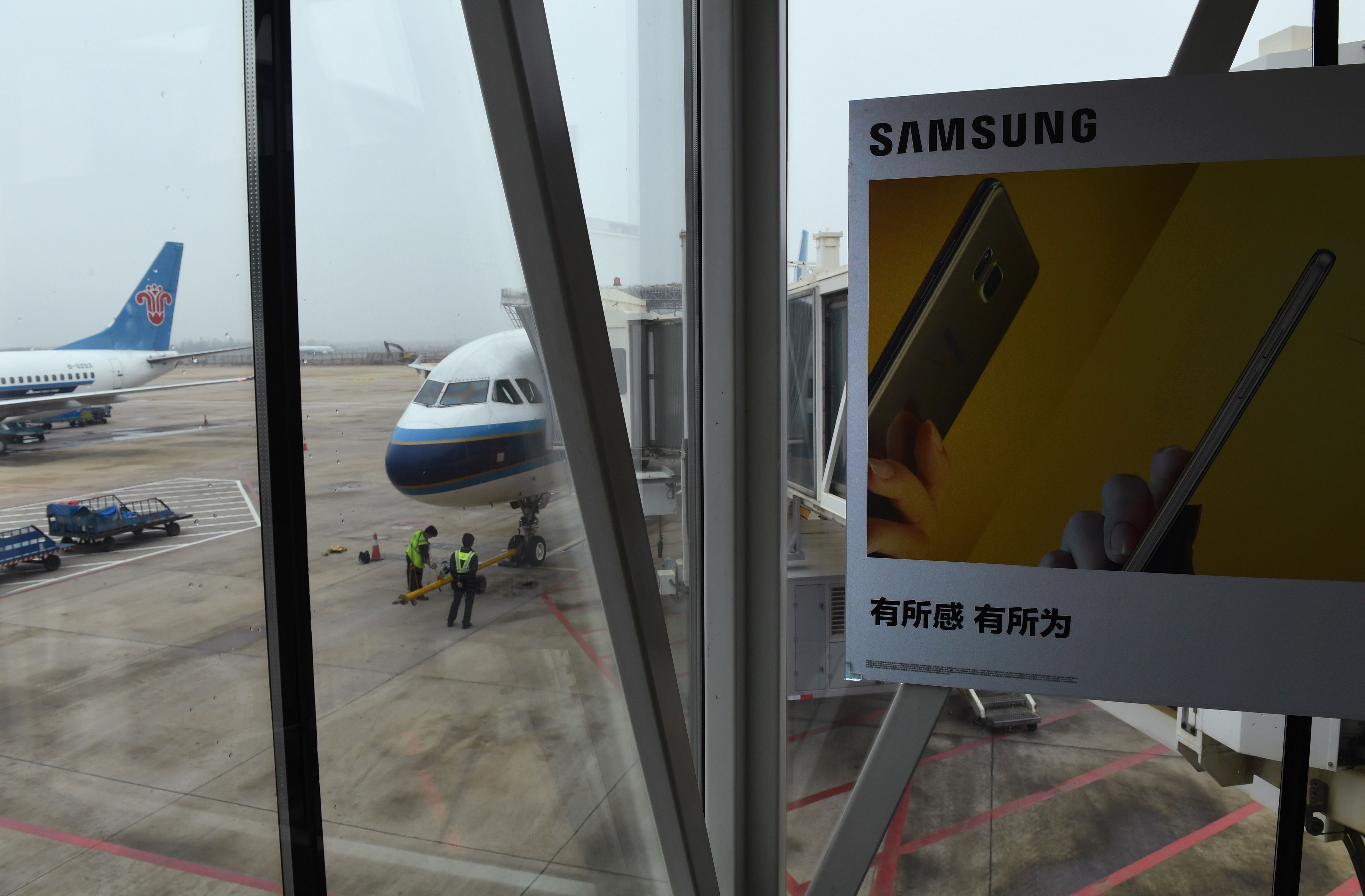 An advertisement for the Samsung Galaxy Note 7 smartphone is seen on an air bridge leading to a plane at the airport in Wuhan, in China's central Hubei province on October 2, 2016. Signs at the Wuhan airport check-in counters warn passengers not to switc
