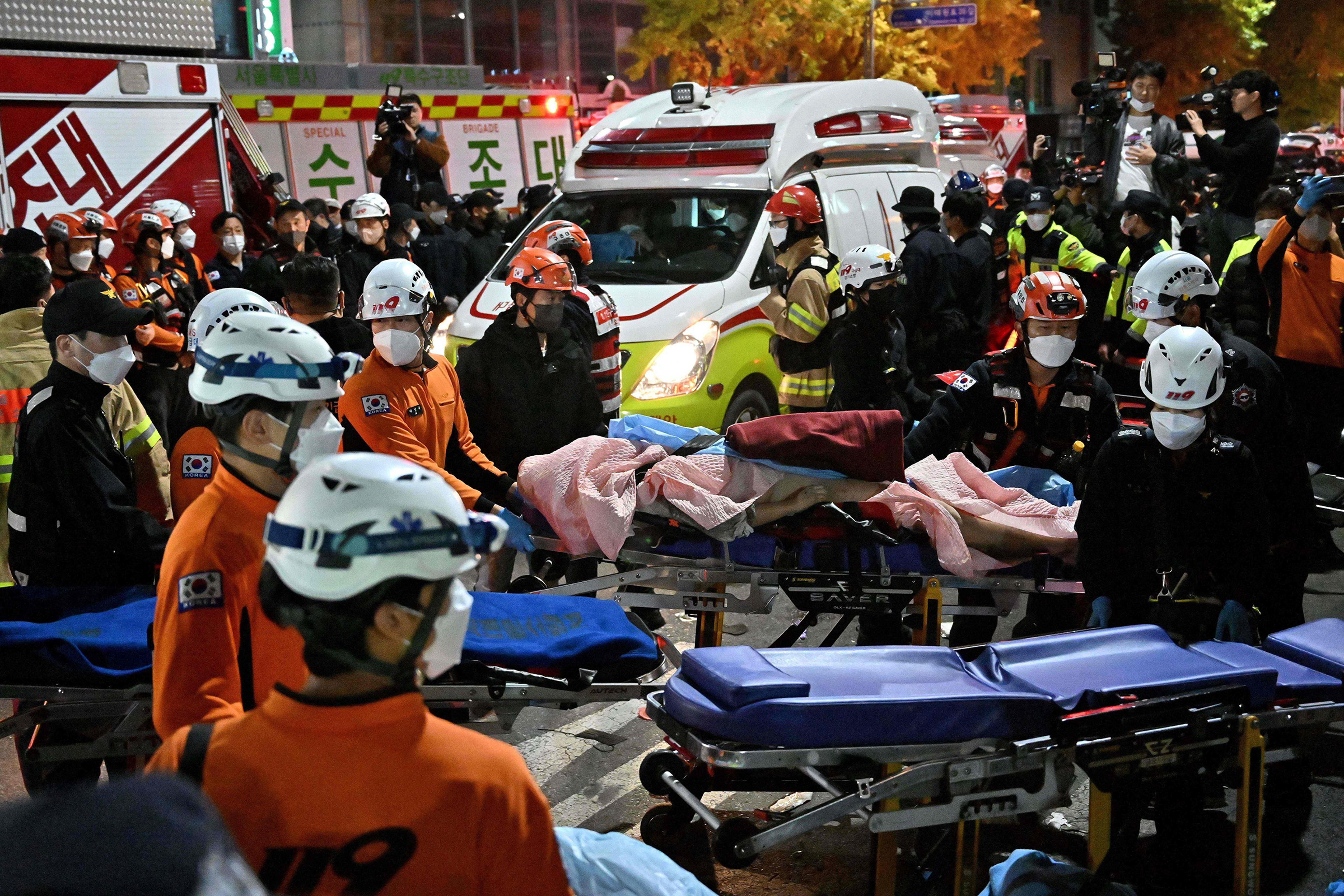 Medical staff transport a victim of a Halloween crush on a stretcher in Itaewon, Seoul on Oct. 30, 2022. At least 120 people were killed and some 100 were injured in a stampede in central Seoul when thousands crowded into narrow streets to celebrate Hall