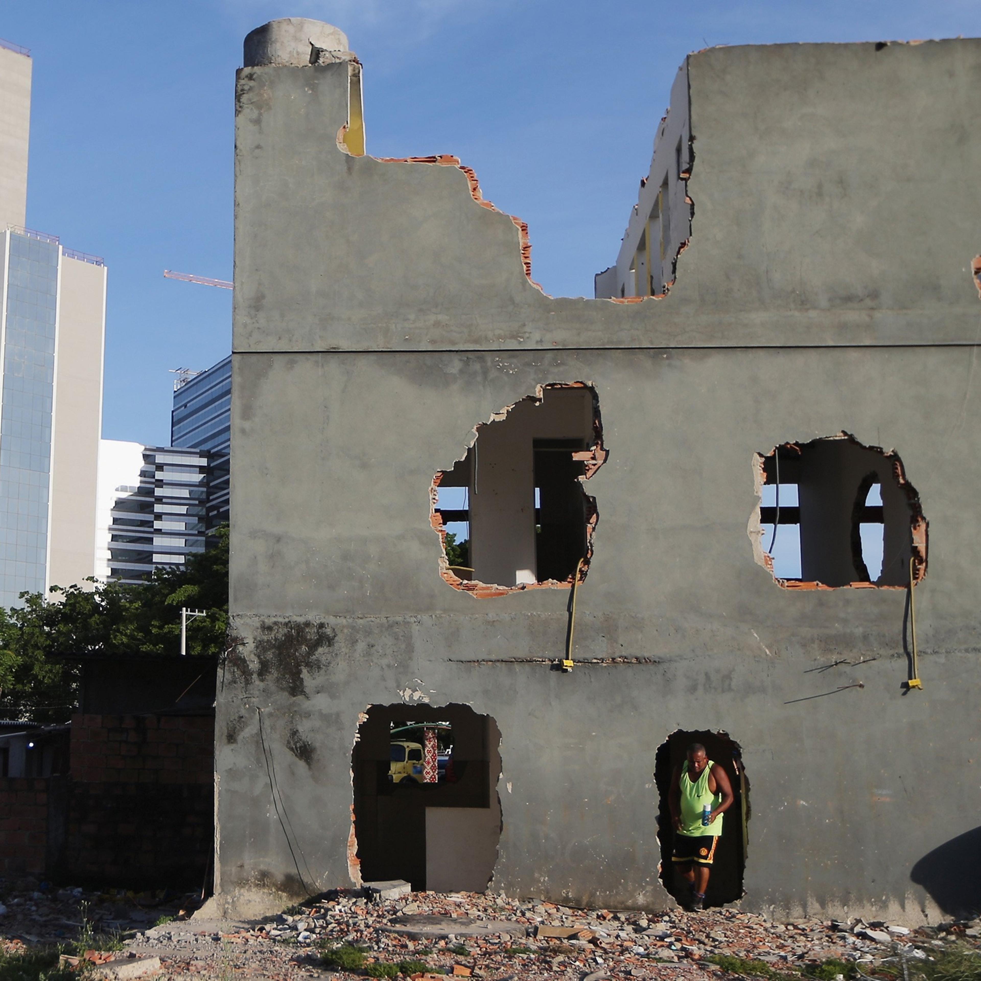 A former resident walks out of a partially demolished building after bringing food and water to a dog inside in the mostly demolished Vila Autodromo favela community, a former fishing colony, on January 6, 2016 in Rio de Janeiro, Brazil.