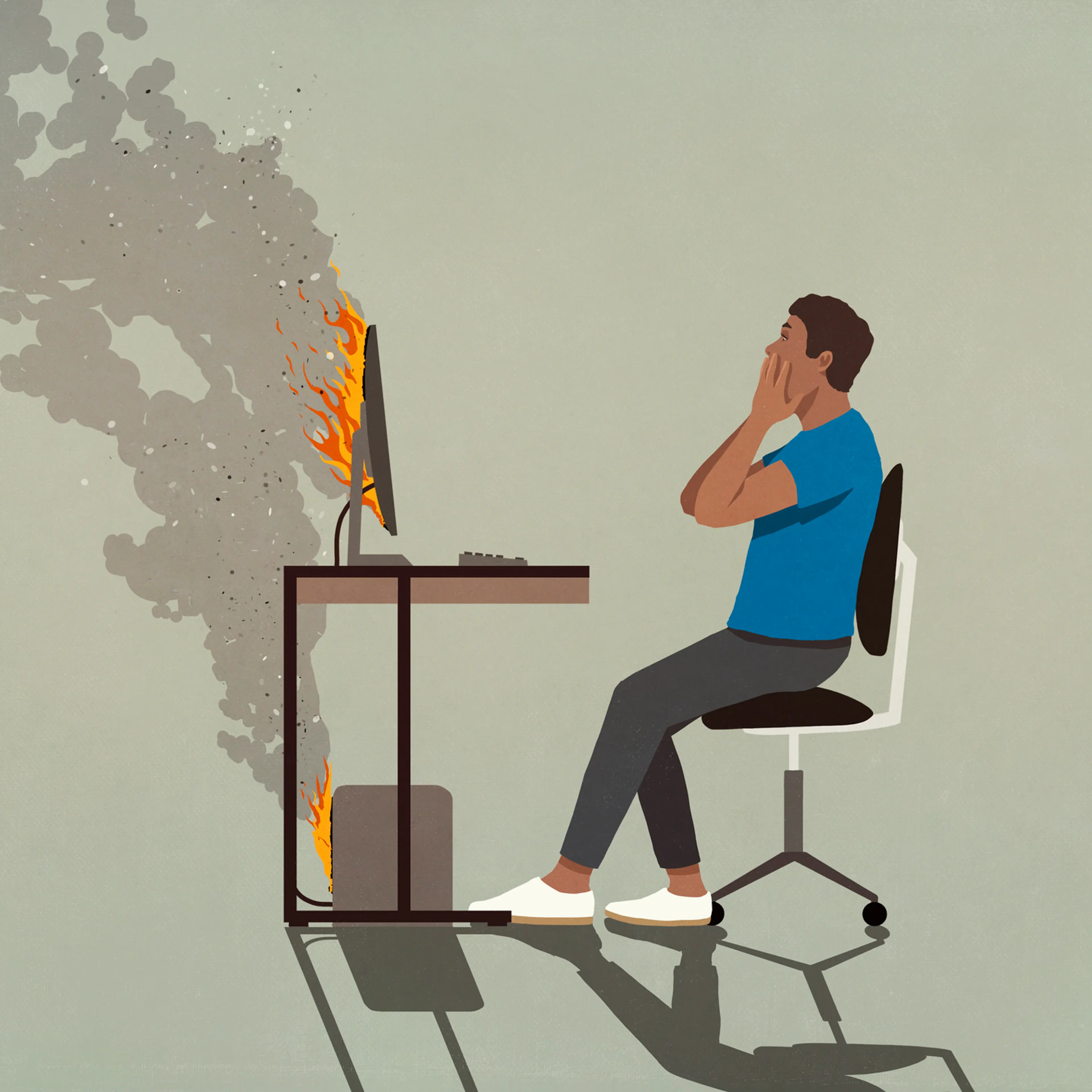 Shocked man sitting at smoking computer on fire