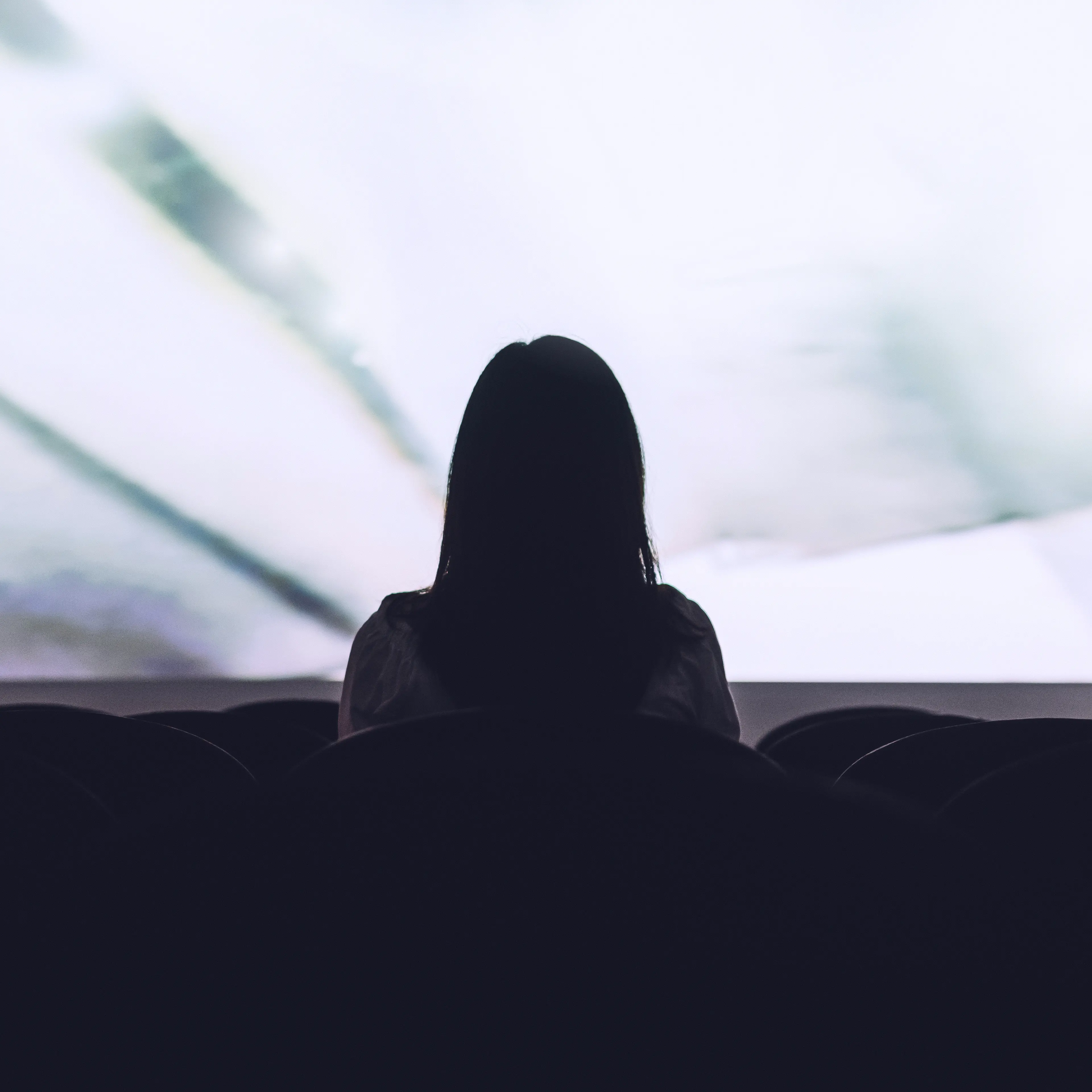 Rear view of woman sitting alone watching movie in empty theatre