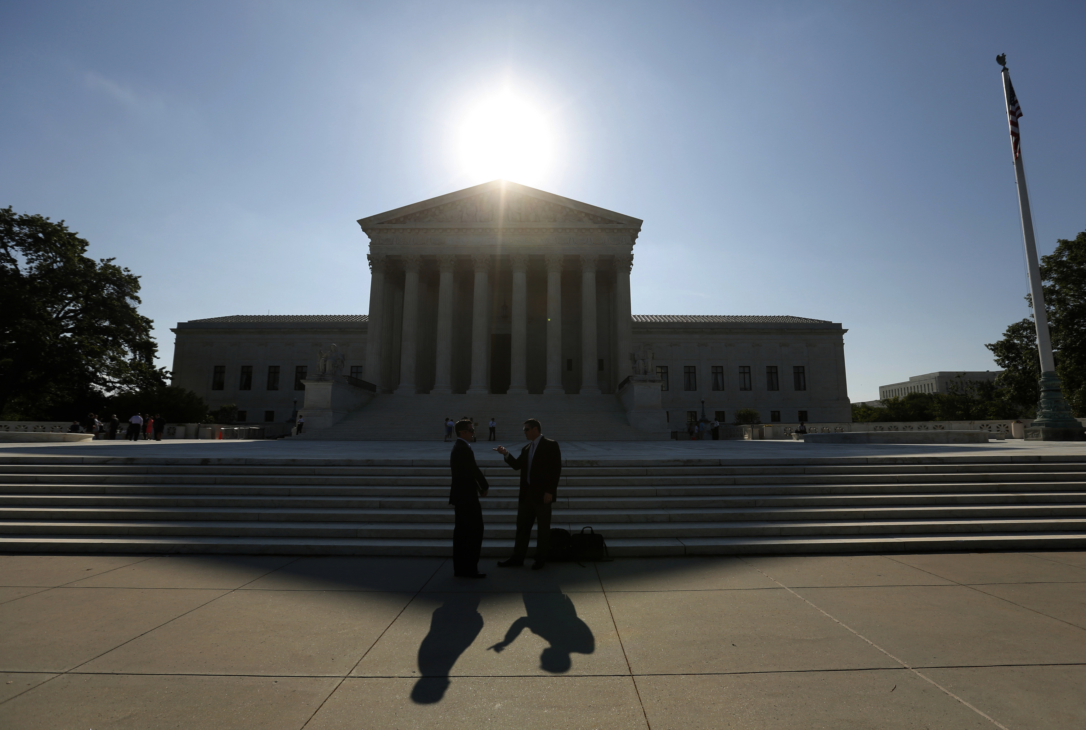 Two men talk as the sun rises over the Supreme Court in Washington