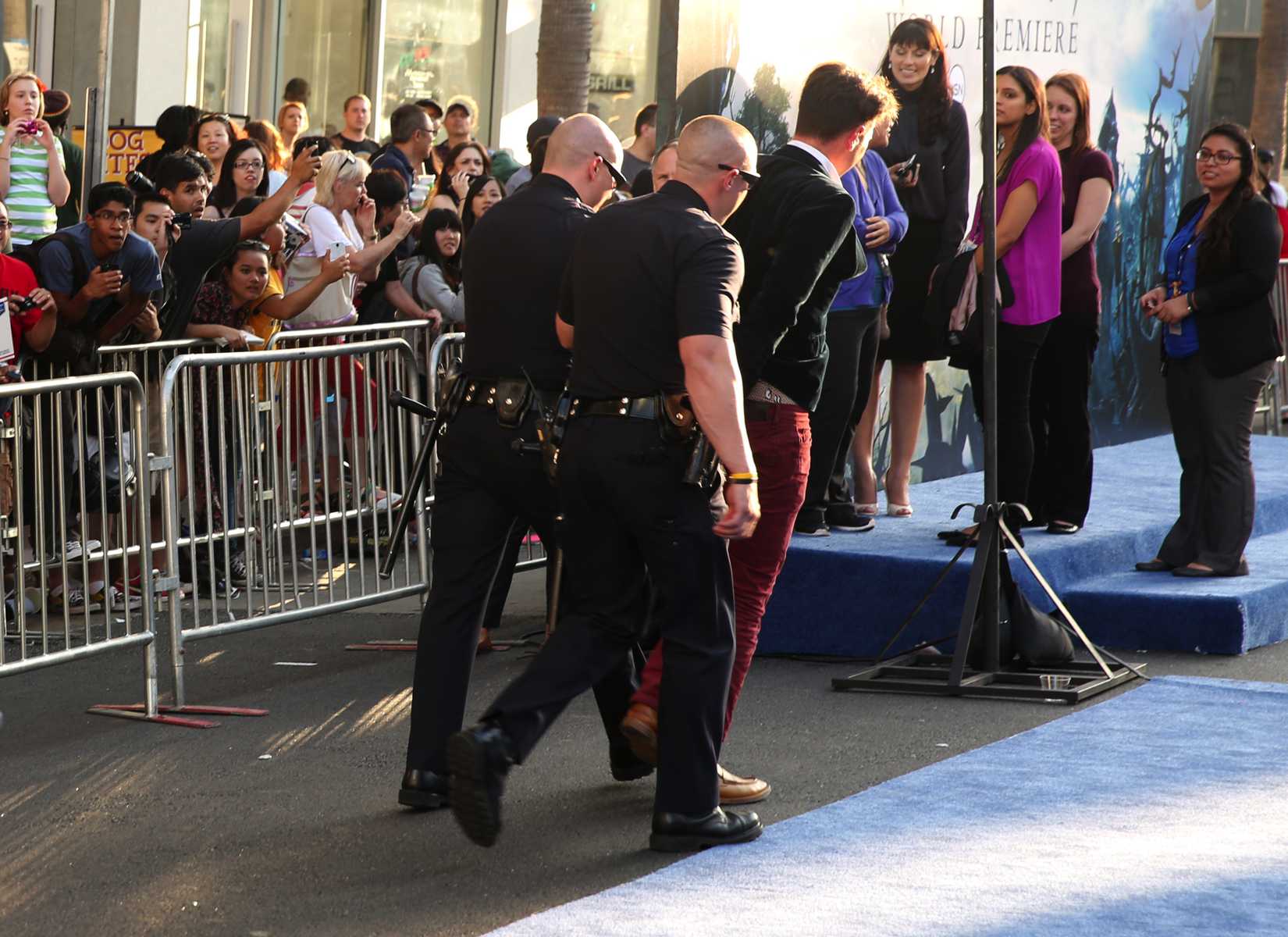 A man is walked off carpet in handcuffs after allegedly attacking Brad Pitt at the world premiere of "Maleficent" at the El Capitan Theatre on Wednesday, May 28, 2014, in Los Angeles.