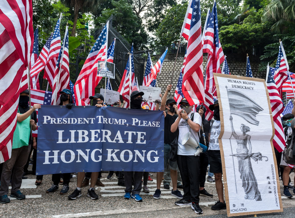 Protesters wave American flags while carrying placards