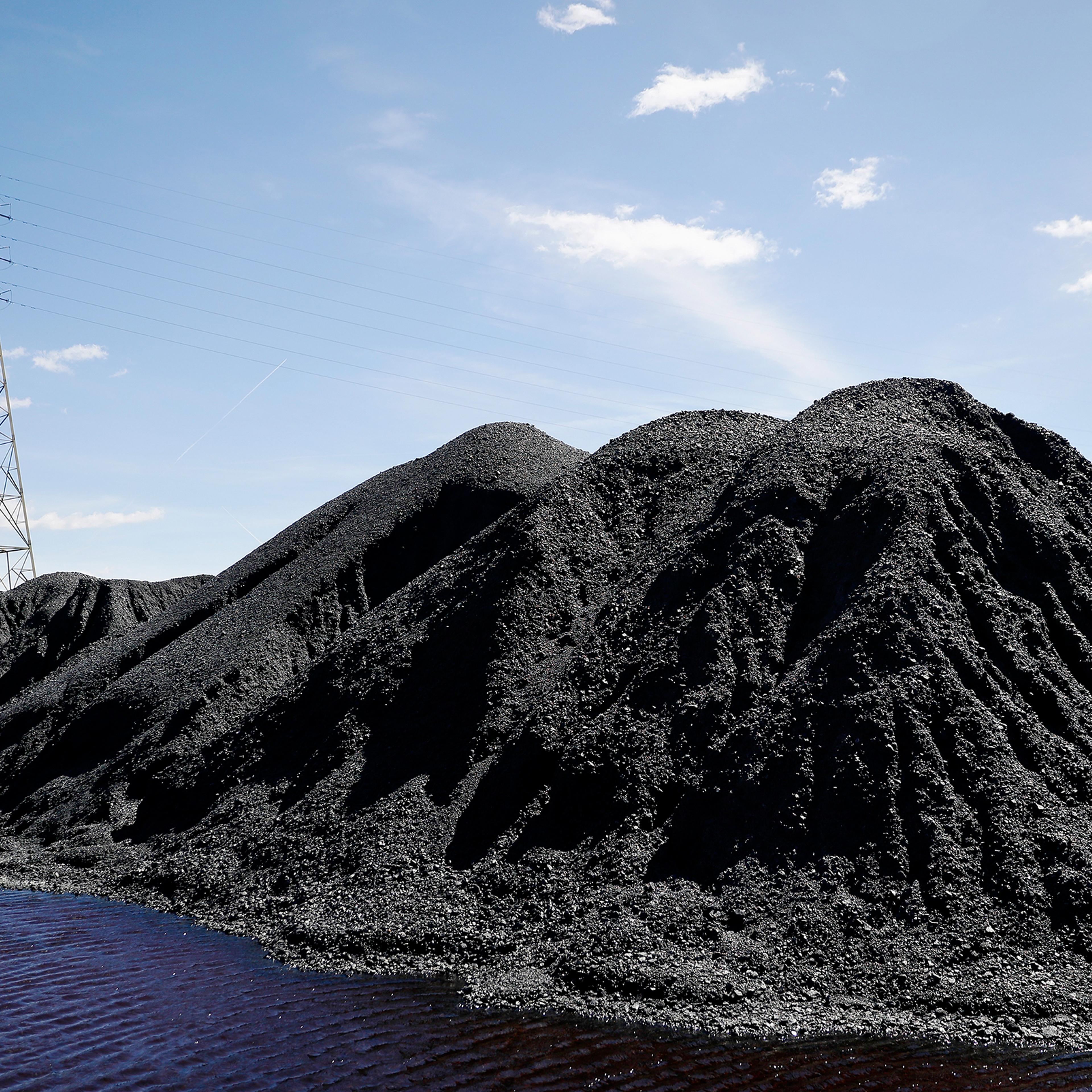 Power lines loom behind piles of coal stored at a facility along the Ohio River in April