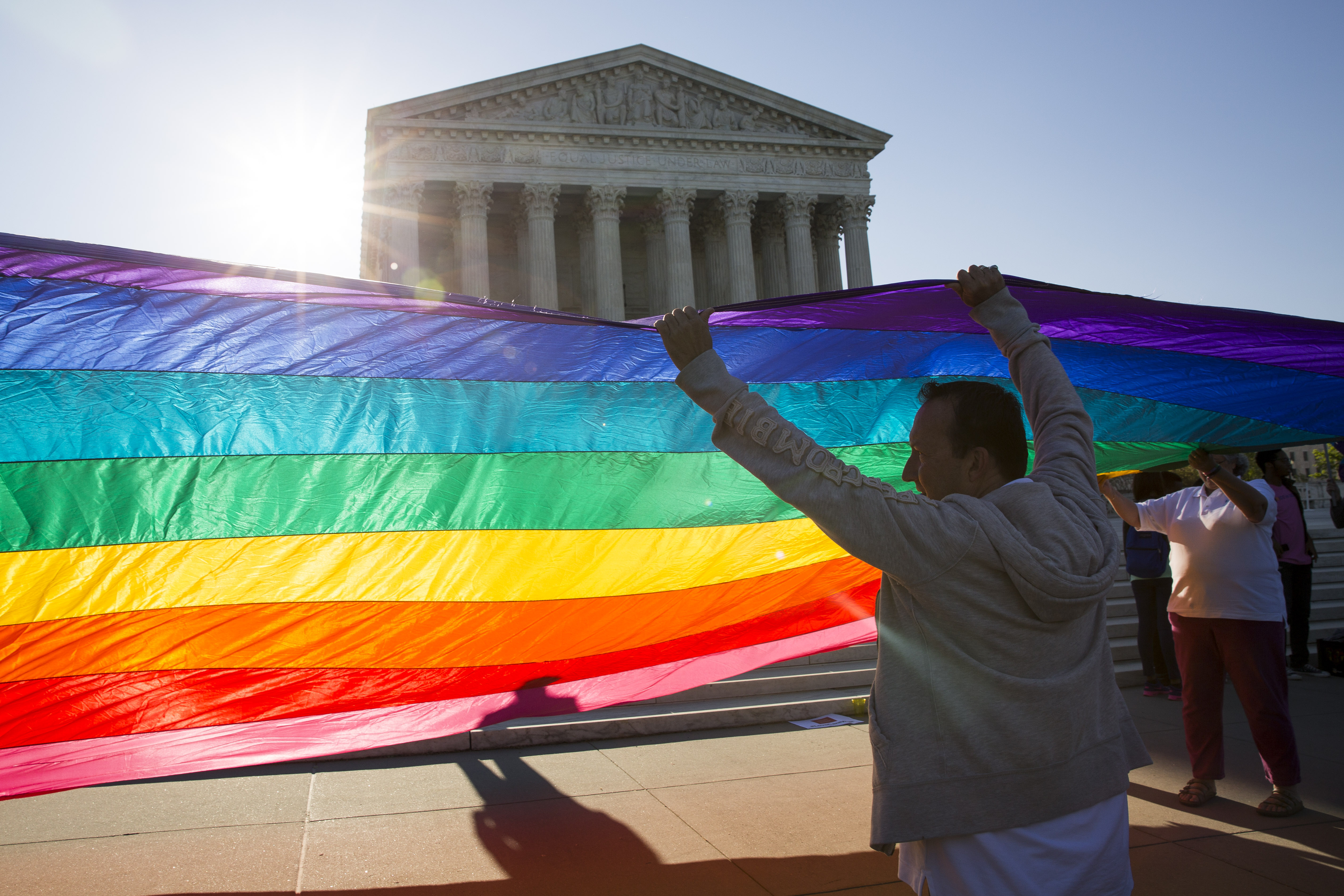 Supporters of same-sex marriage unfurl a large rainbow pride flag near the Supreme Court on April 28, 2015 in Washington.