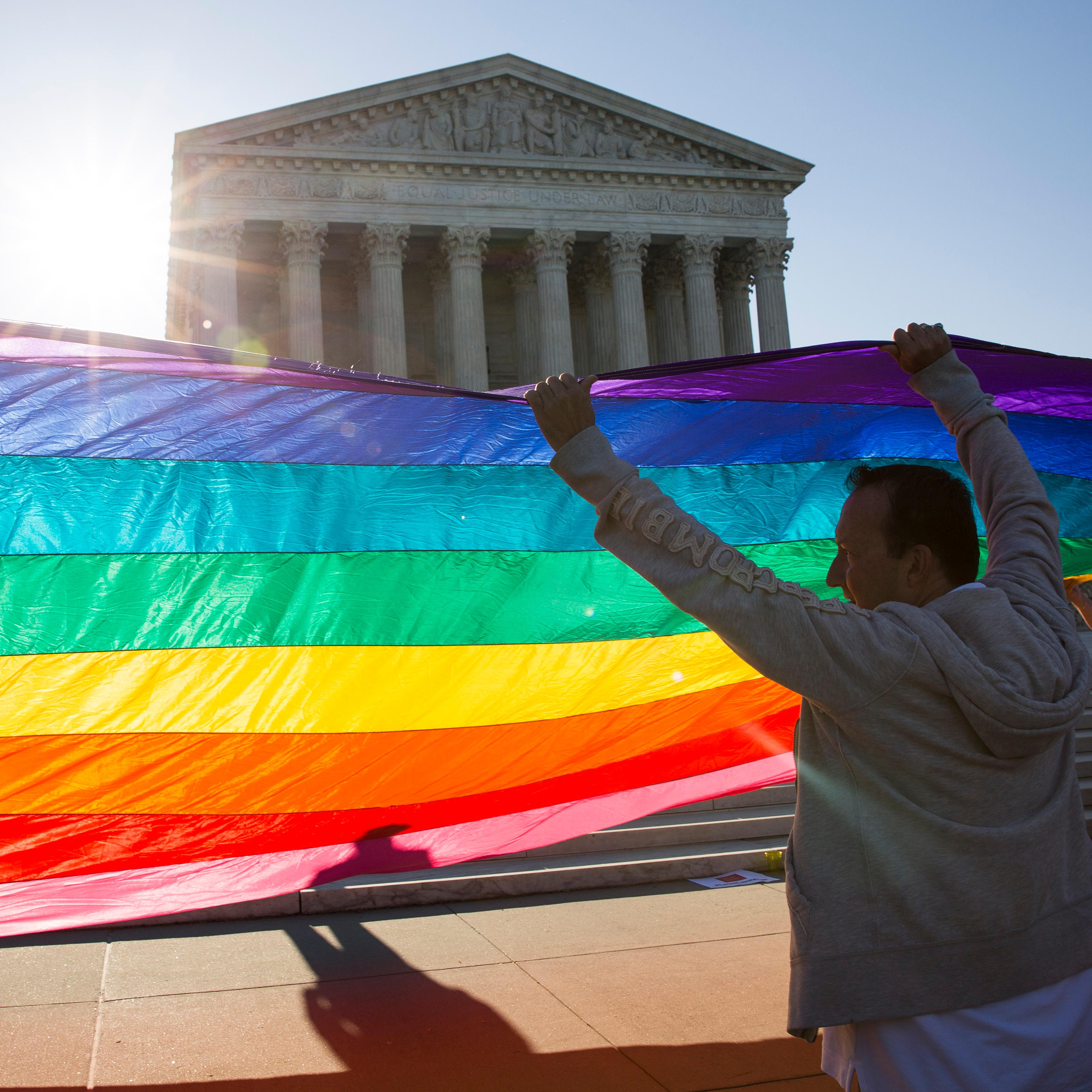 Supporters of same-sex marriage unfurl a large rainbow pride flag near the Supreme Court on April 28, 2015 in Washington.