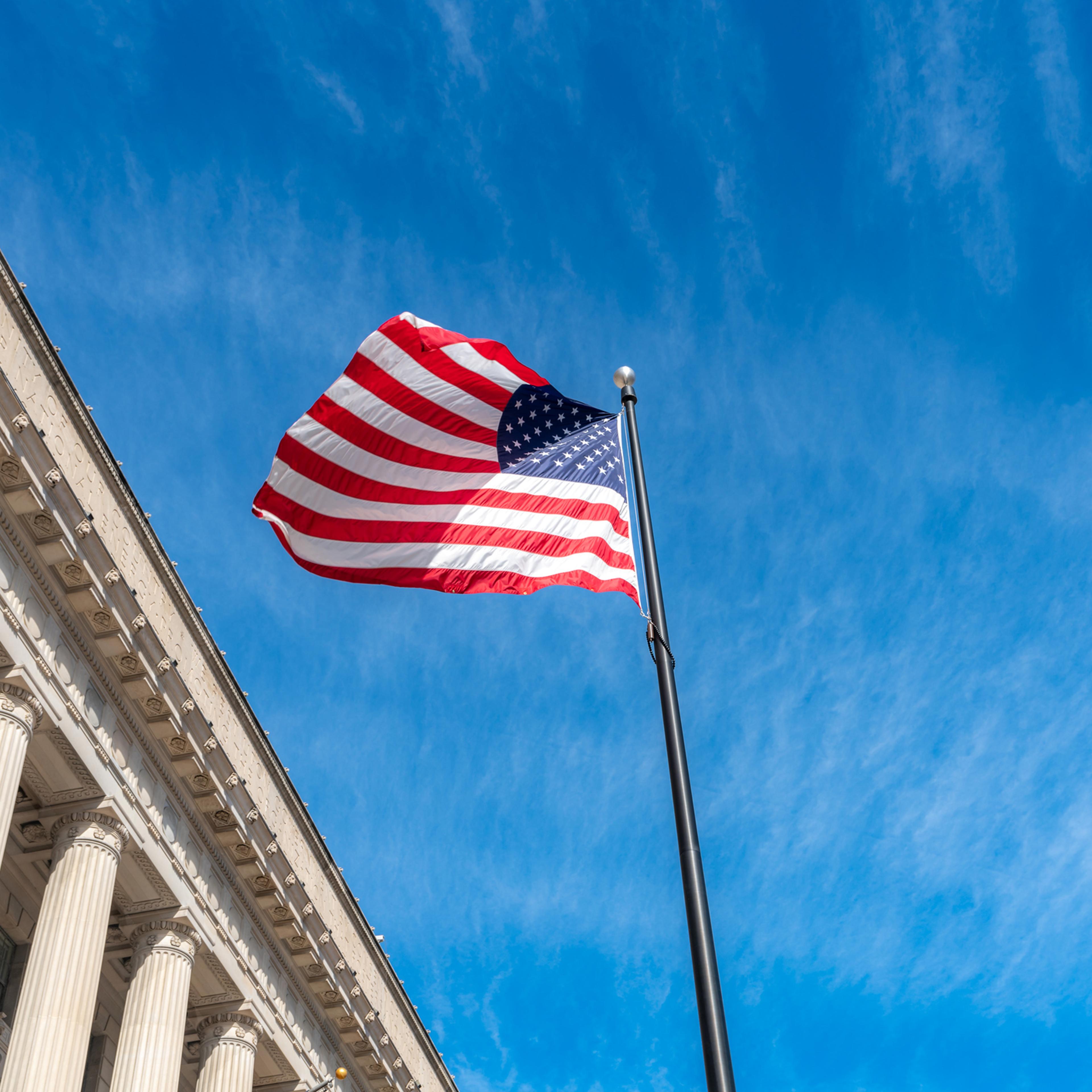 American flag flapping boldly in the wind with The Supreme Court in Washington DC, USA.