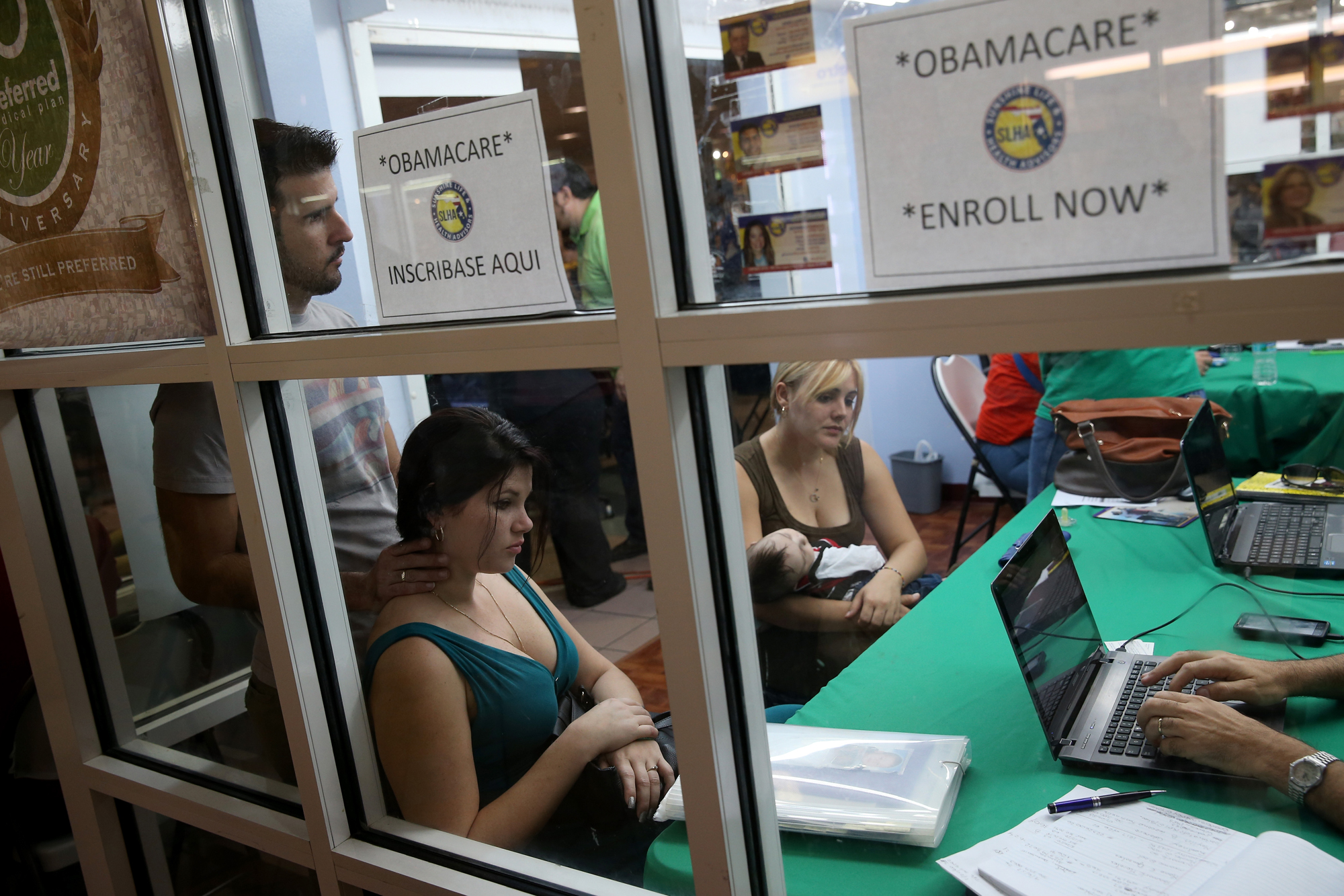 Ronnie Cabrera, Dailem Delombard and Maylin Lezcano holding Lucas Cabrera sit with an insurance agent from Sunshine Life and Health Advisors as they try to purchase health insurance under the Affordable Care Act at the kiosk setup at the Mall of Americas