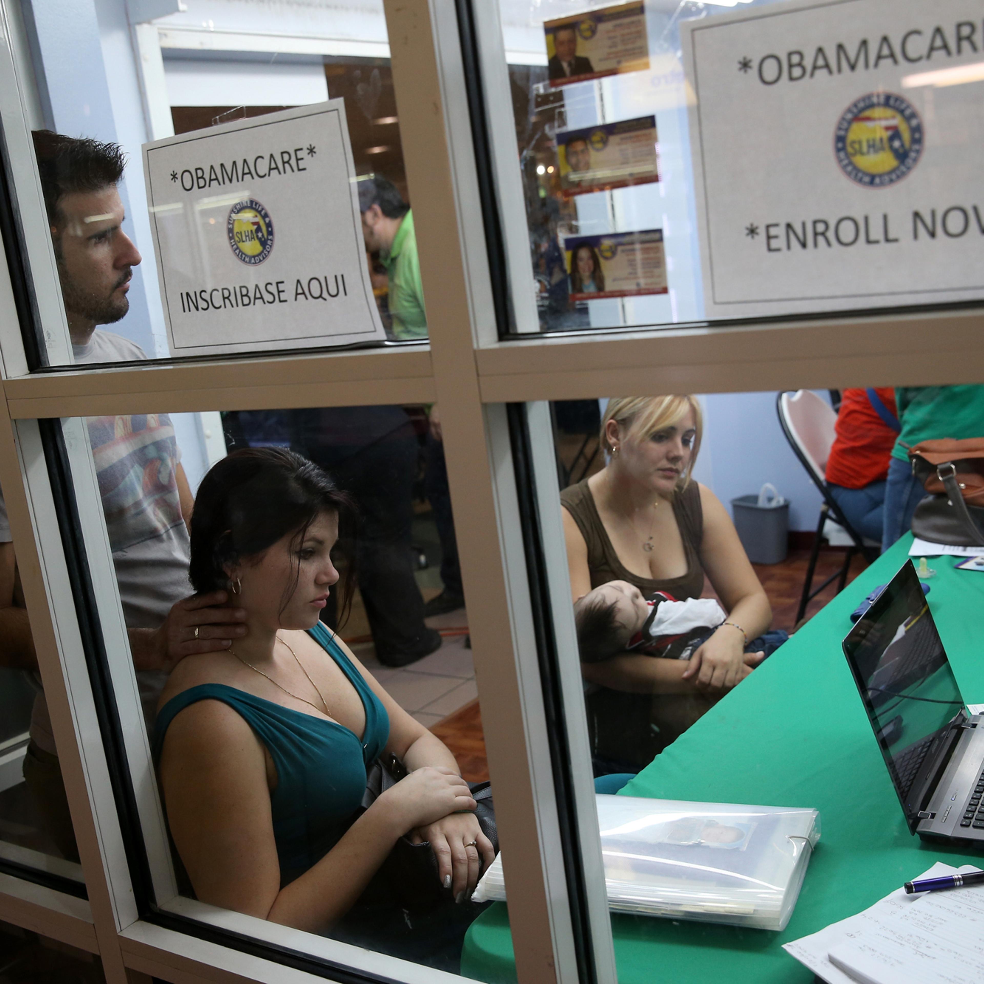 Ronnie Cabrera, Dailem Delombard and Maylin Lezcano holding Lucas Cabrera sit with an insurance agent from Sunshine Life and Health Advisors as they try to purchase health insurance under the Affordable Care Act at the kiosk setup at the Mall of Americas