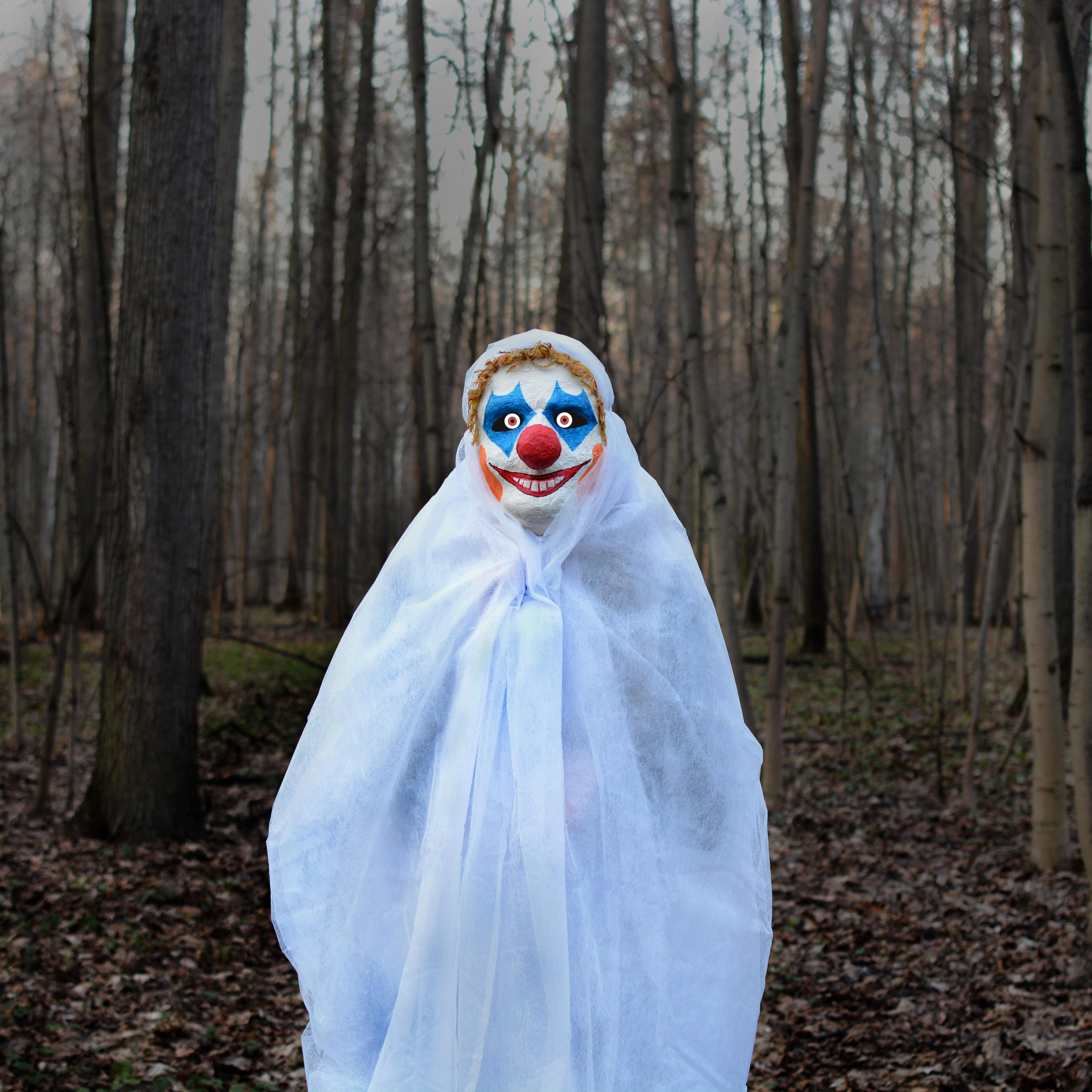 evil clown in a dark forest in a white veil