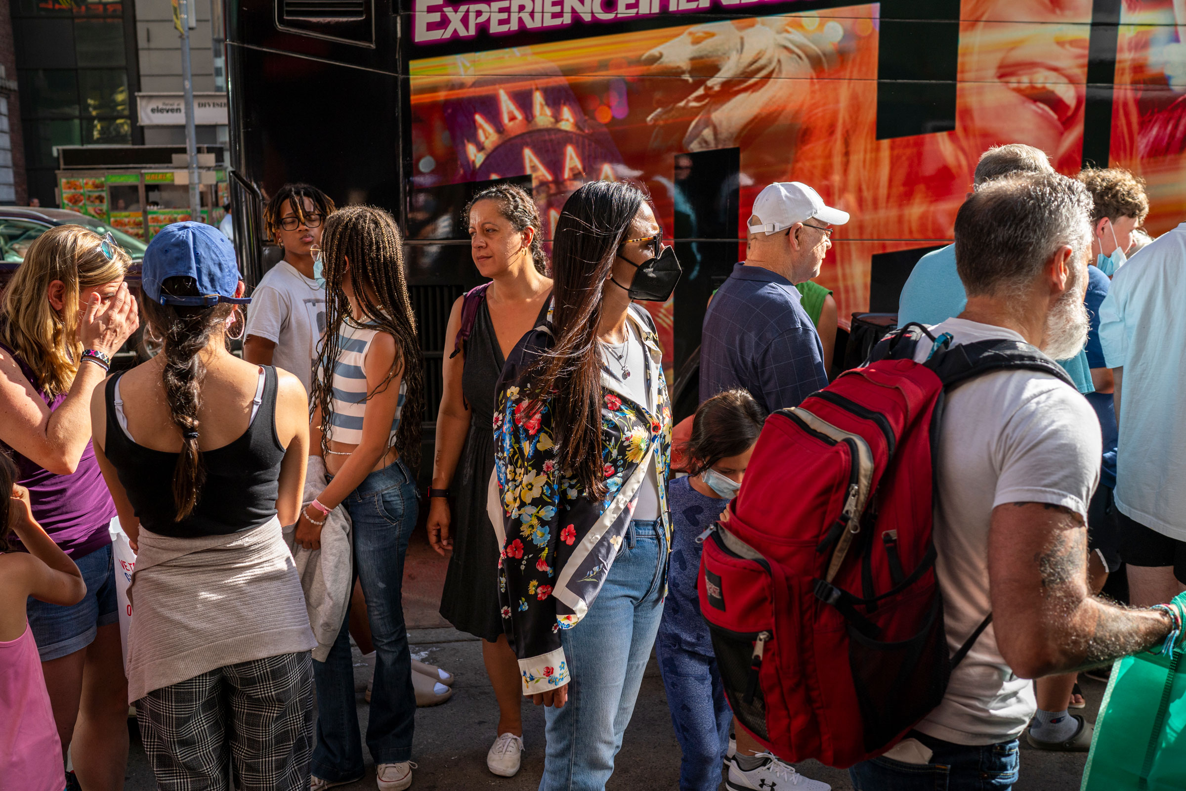 Tourists holding tickets for a bus tour stand in line