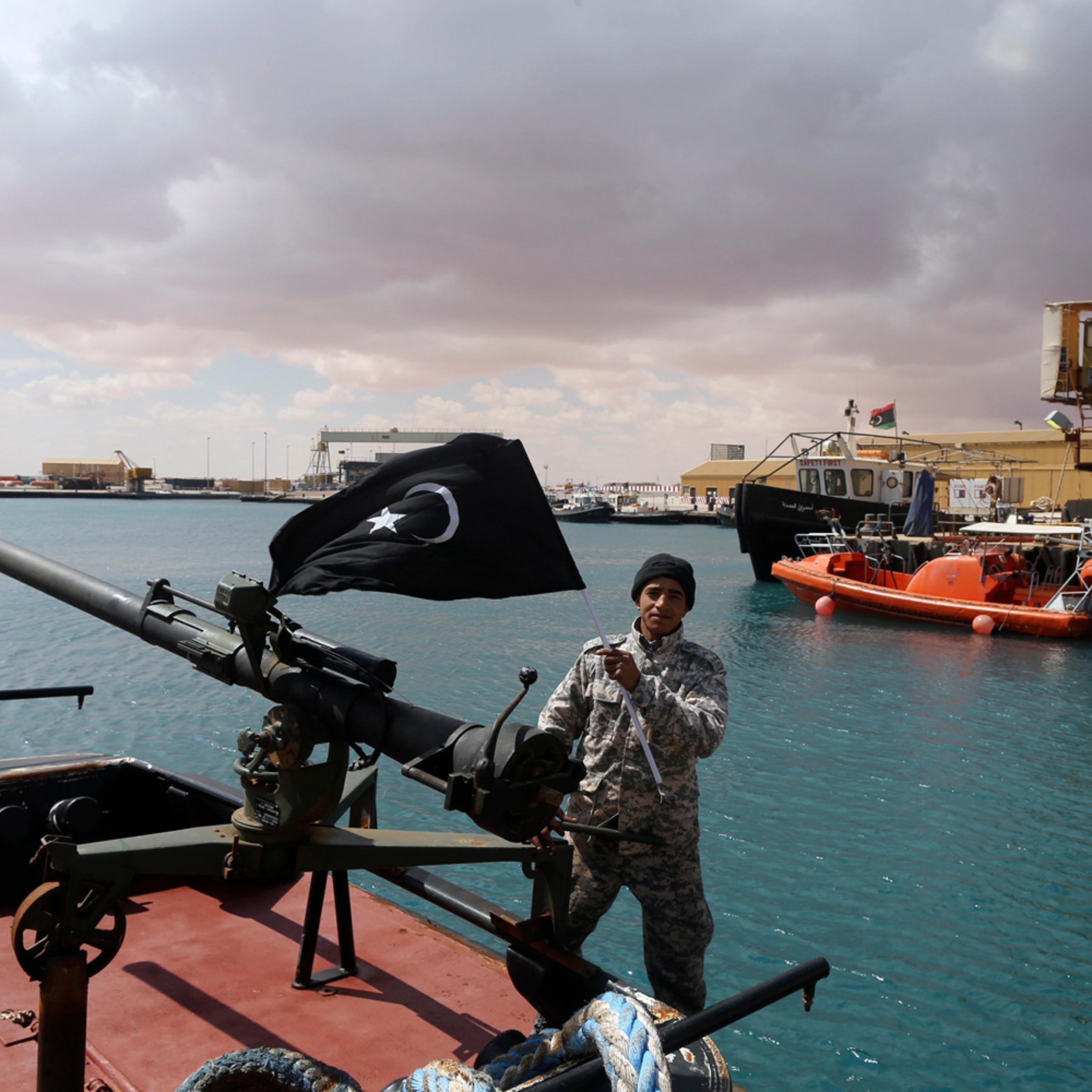 A rebel under Ibrahim Jathran holds the Cyrenaica flag while standing on a boat at Es Sider port in Ras Lanuf