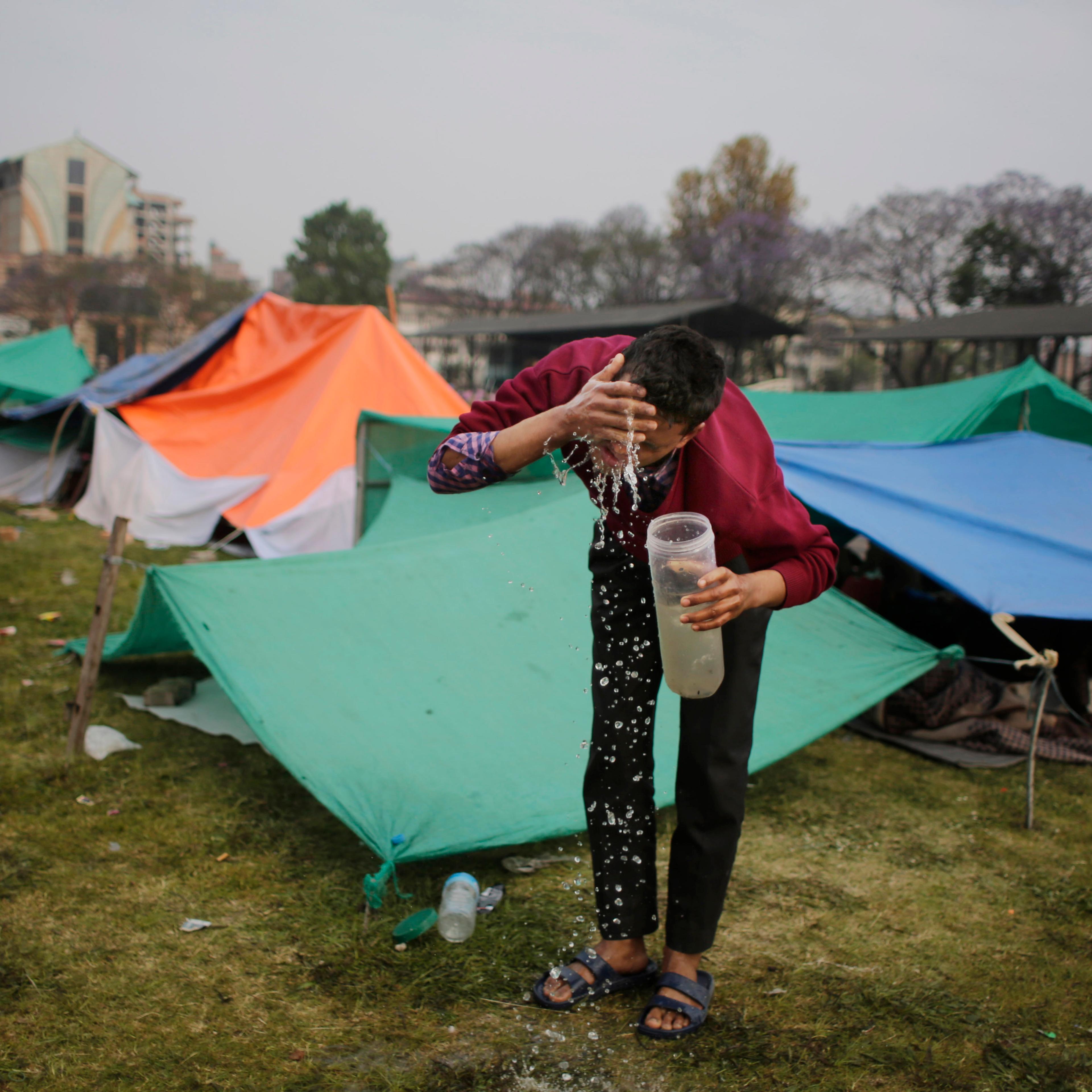Survivor of Saturday's earthquake washes his face after spending night in an open ground from fears of earthquake tremors in Kathmandu, Nepal, Tuesday, April 28, 2015.