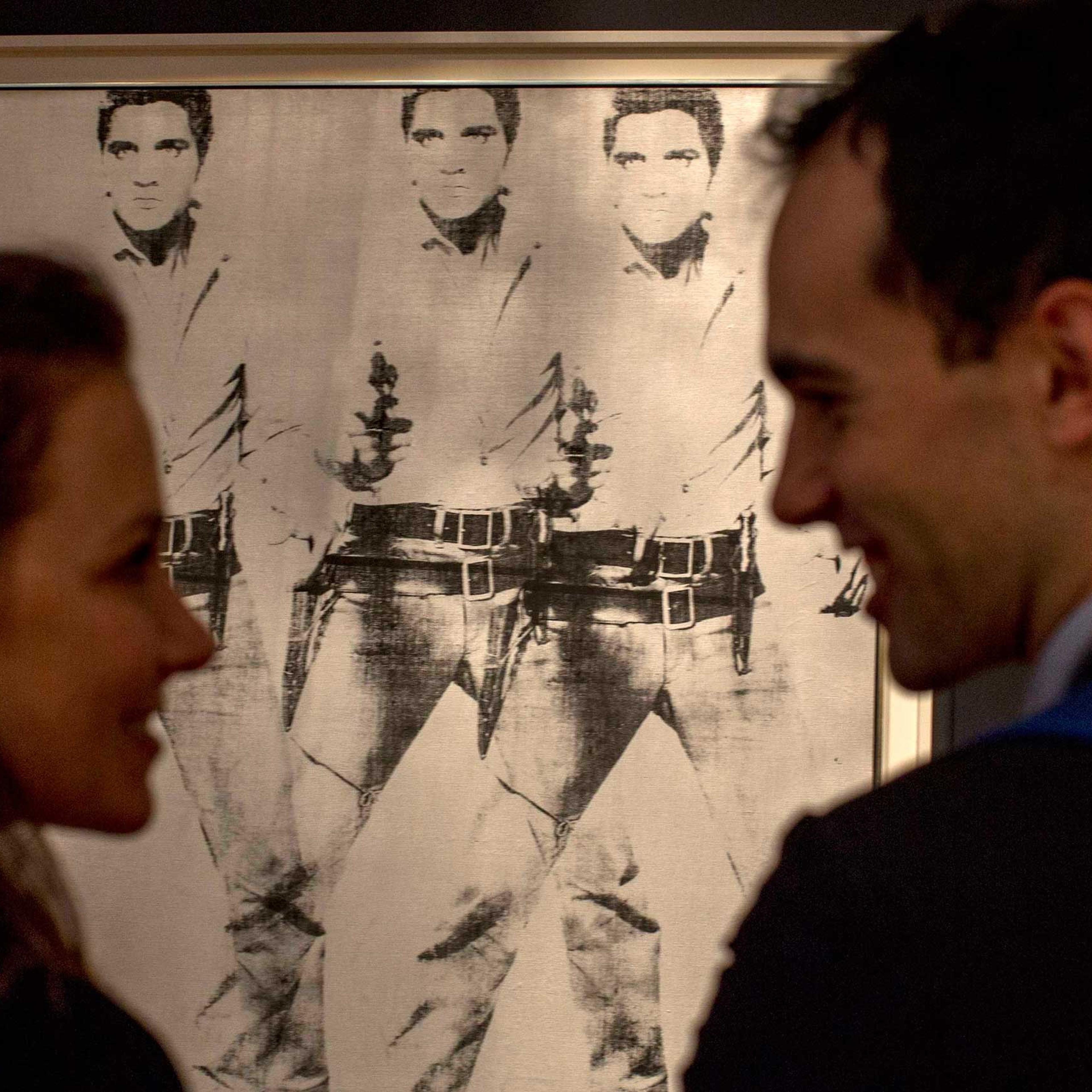 A couple talk in front of "Triple Elvis" by Andy Warhol during a media preview at Christie's auction house in New York, October 31, 2014.