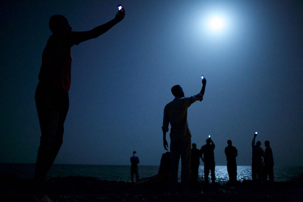World Press Photo of the Year 2013.
<br />
<br />
Feb. 26, 2013. African migrants on the shore of Djibouti city at night, raising their phones in an attempt to capture an inexpensive signal from neighboring Somalia. Djibouti is a common stop-off point for migrants in transit from such countries as Somalia, Ethiopia and Eritrea, seeking a better life in Europe and the Middle East.
