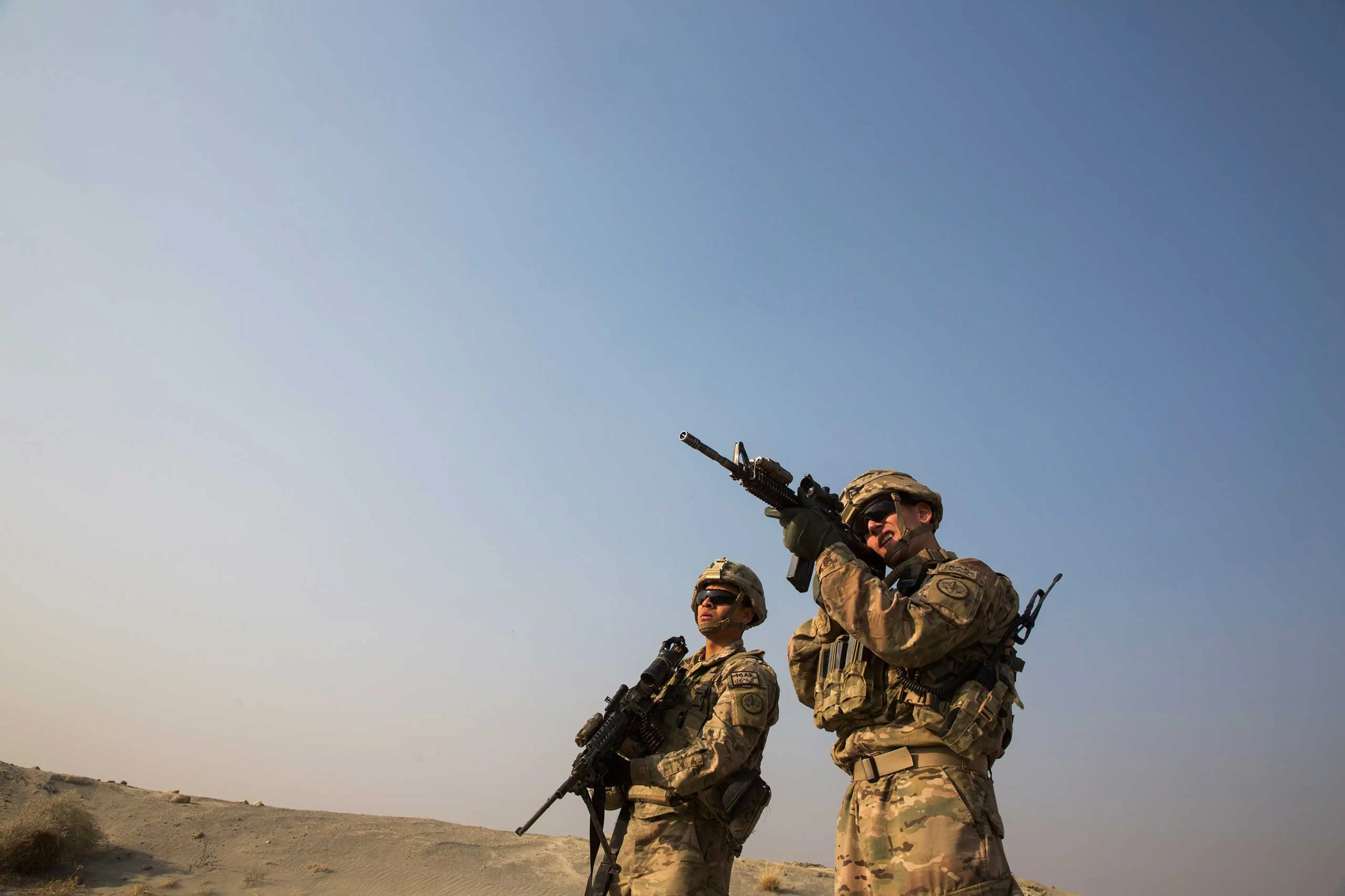 A U.S. soldier from the 3rd Cavalry Regiment uses the optic on his rifle to observe Afghans in the distance, near forward operating base Gamberi, in the Laghman province of Afghanistan