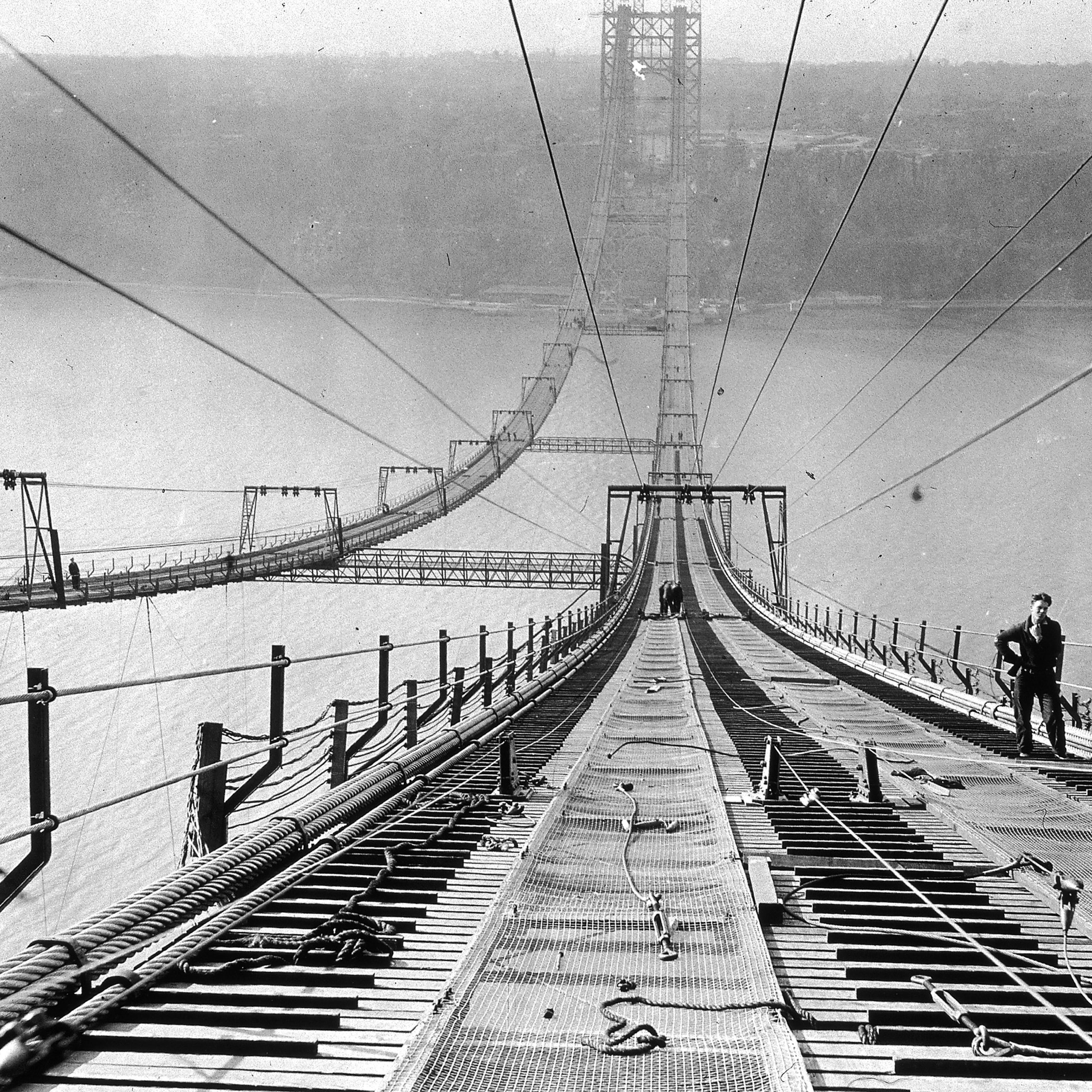 Full-length image of a worker pausing near the top of the George Washington Bridge during its construction, New York City. Circa 1930.