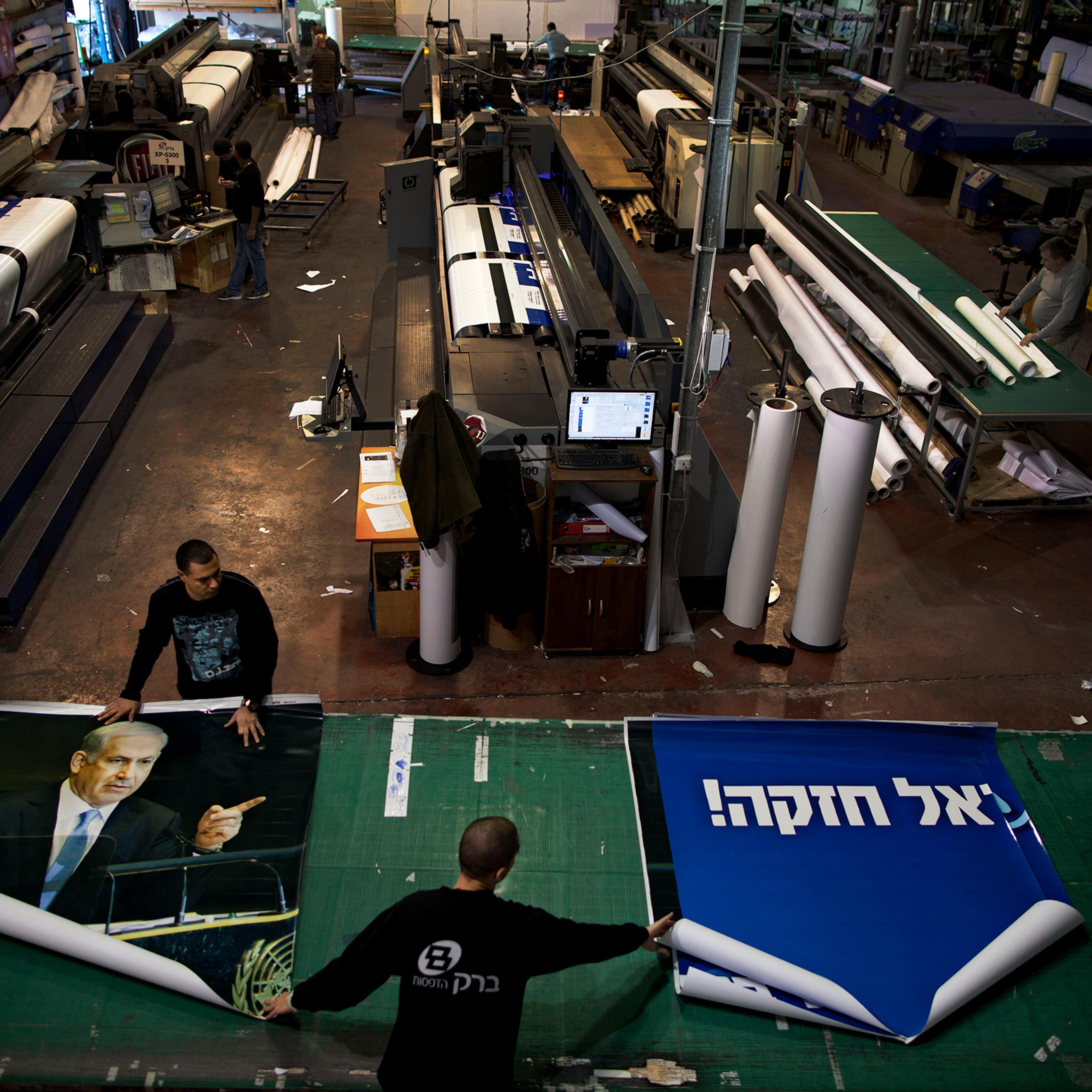Printing house employees work on a campaign billboard for Israeli Prime Minister and Likud Party leader Benjamin Netanyahu in central Petah Tikva in 2013.