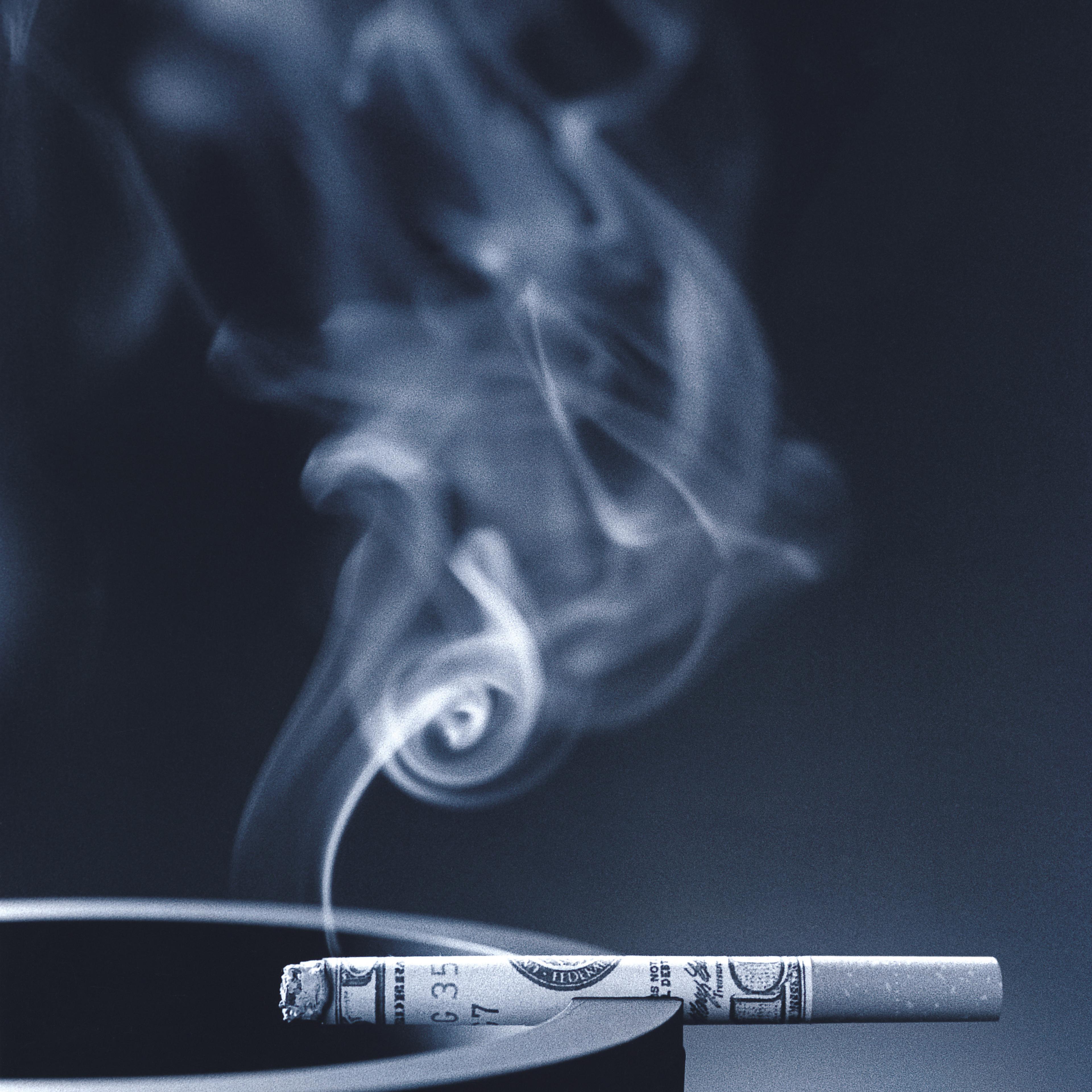 smoking cigarette wrapped in money on ashtray