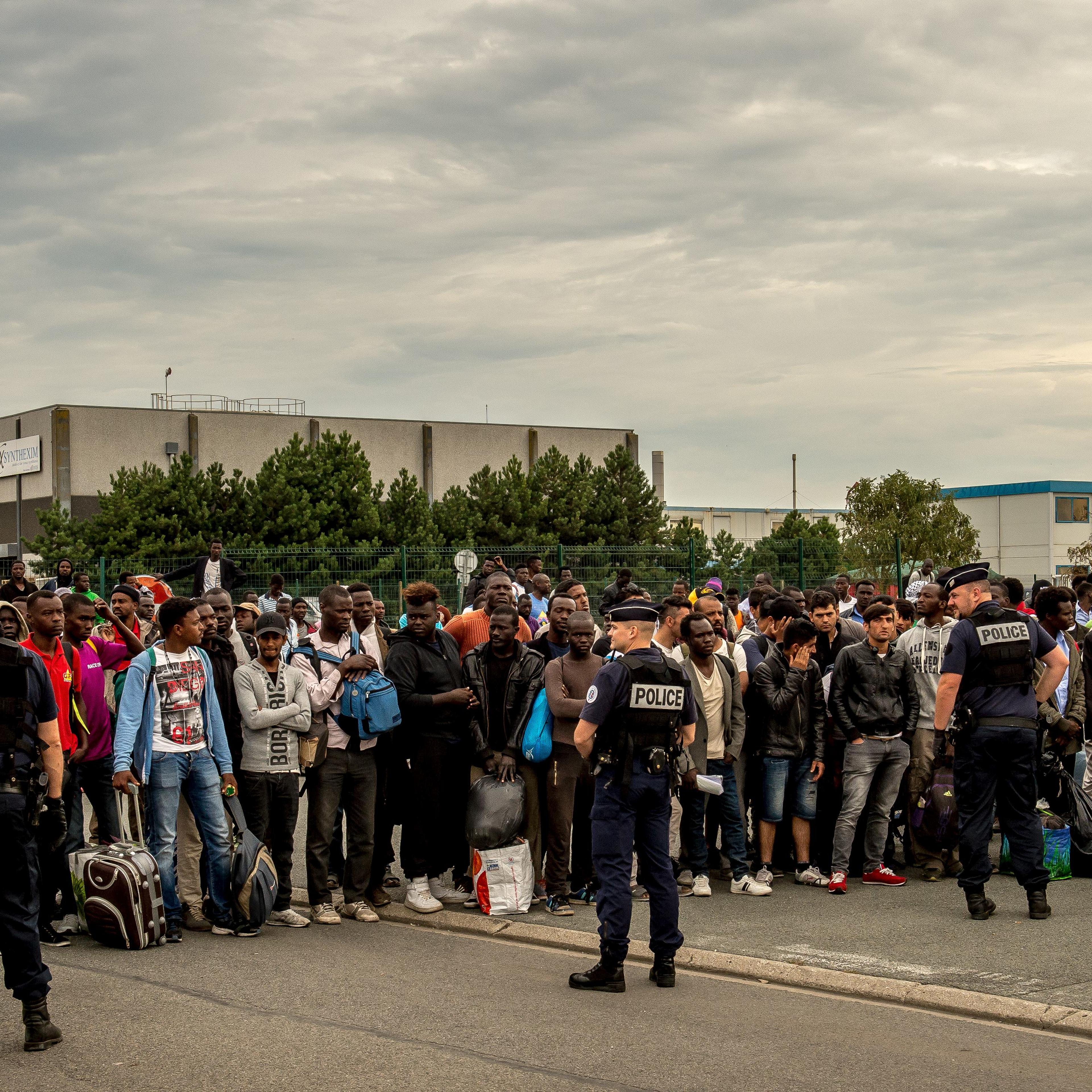 Migrants from the 'Jungle' migrant camp who have been denied access to a bus heading to a "Welcome and orientation centre" (CAO) are gathered under police surveillance, in Calais on Sept. 13, 2016.
