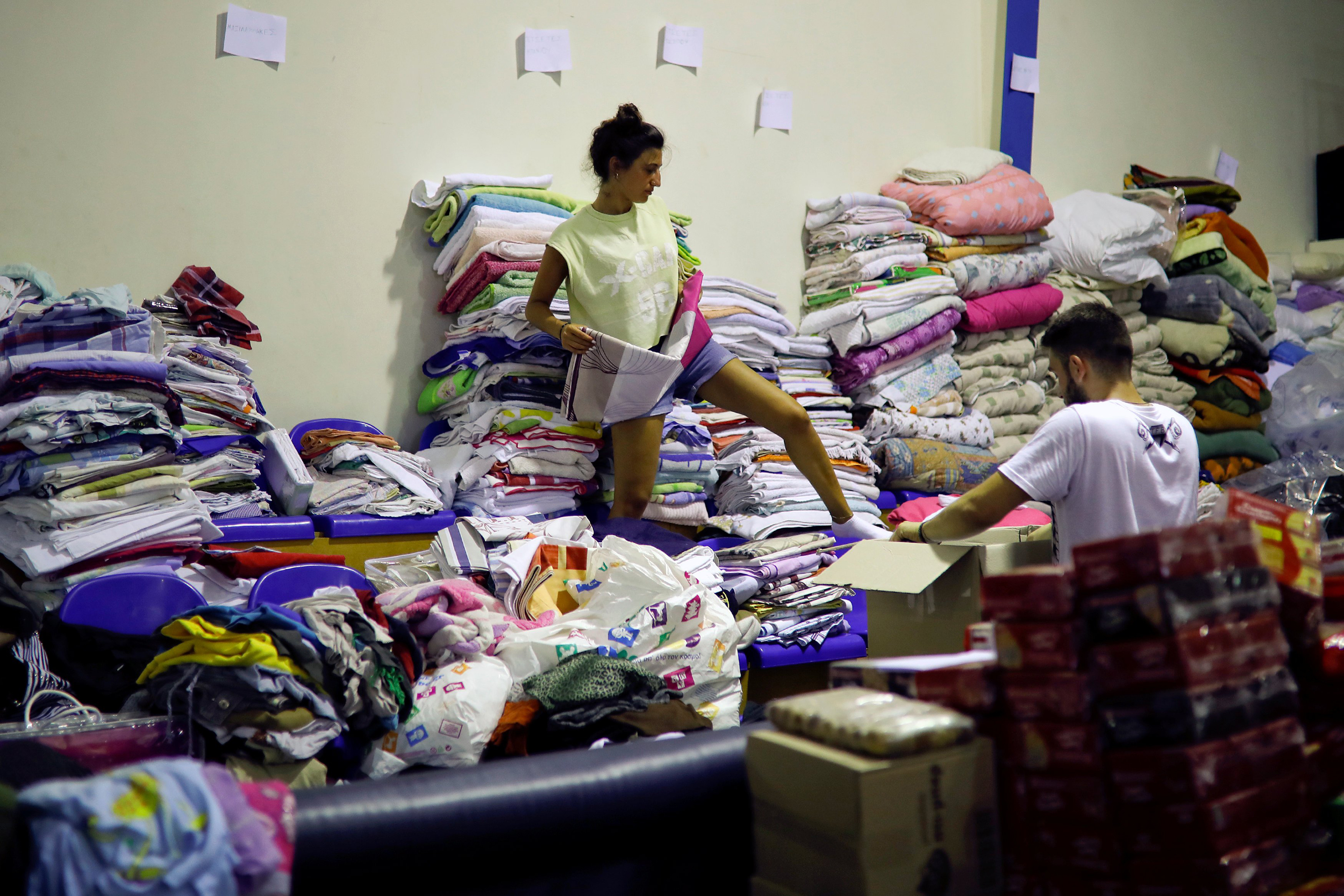 A volunteer arranges clothes for residents of areas that were struck by a wildfire in Nea Makri, near Athens