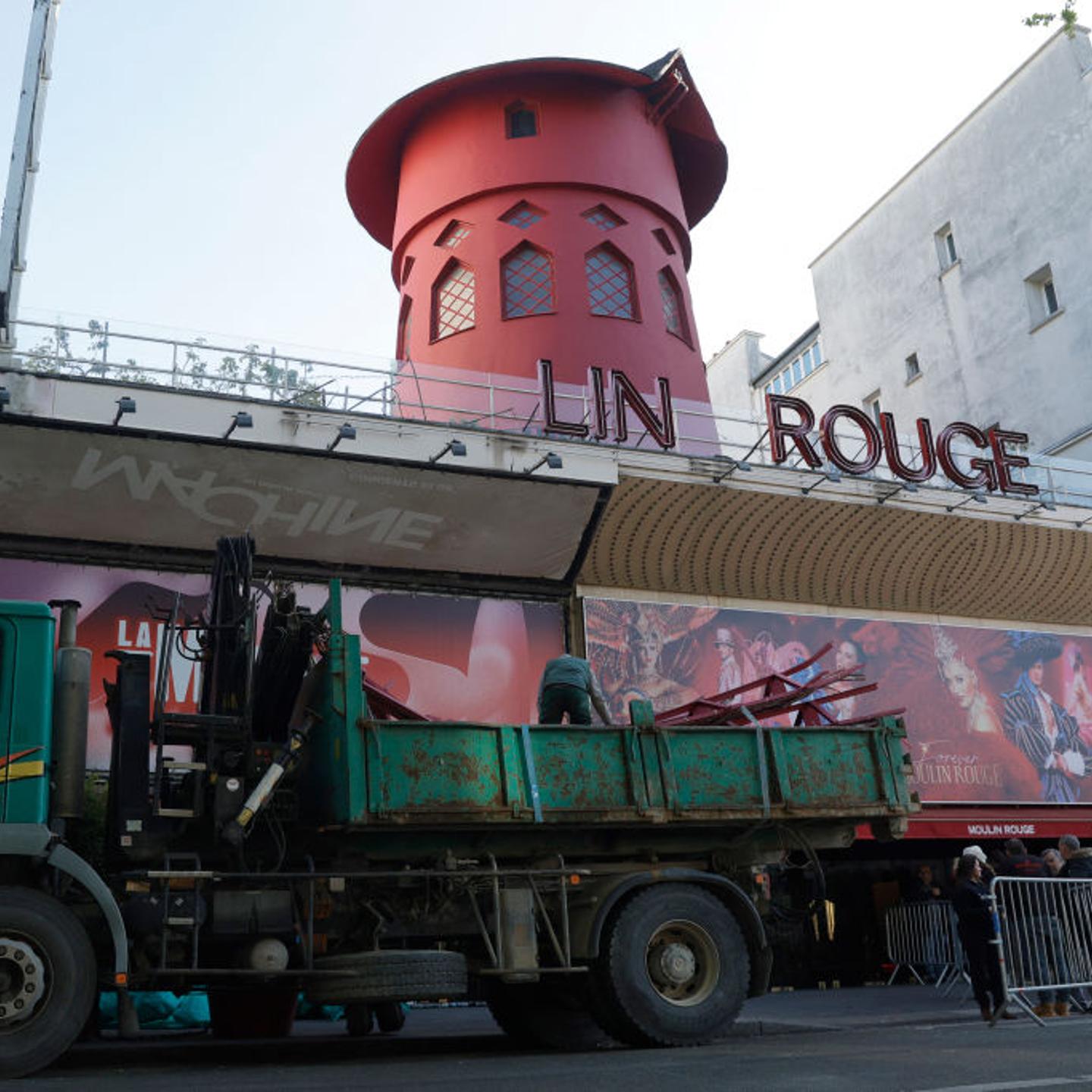 Workers load the blades of the Moulin Rouge windmill collapsed during the night.