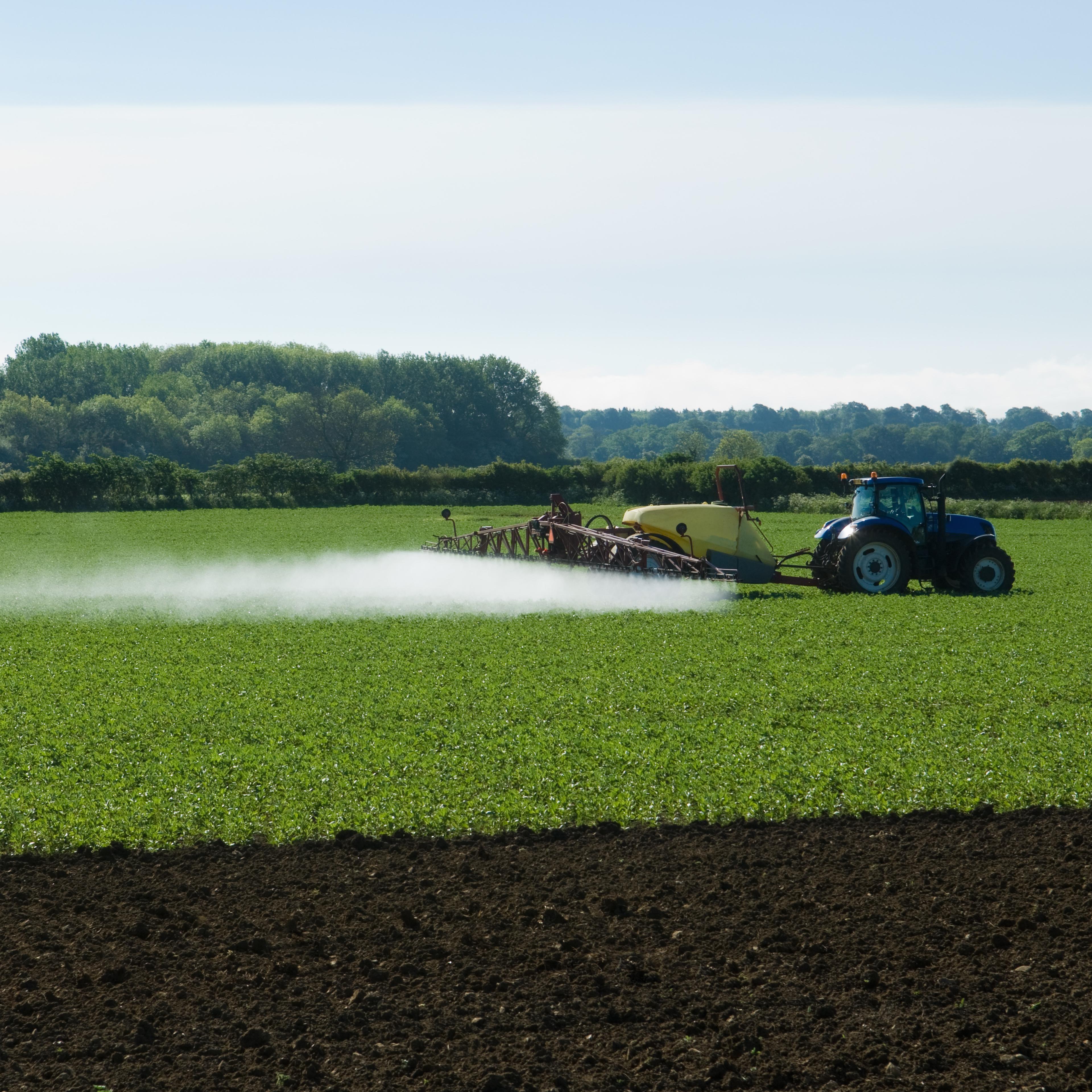Tractor and crop sprayer spraying in field