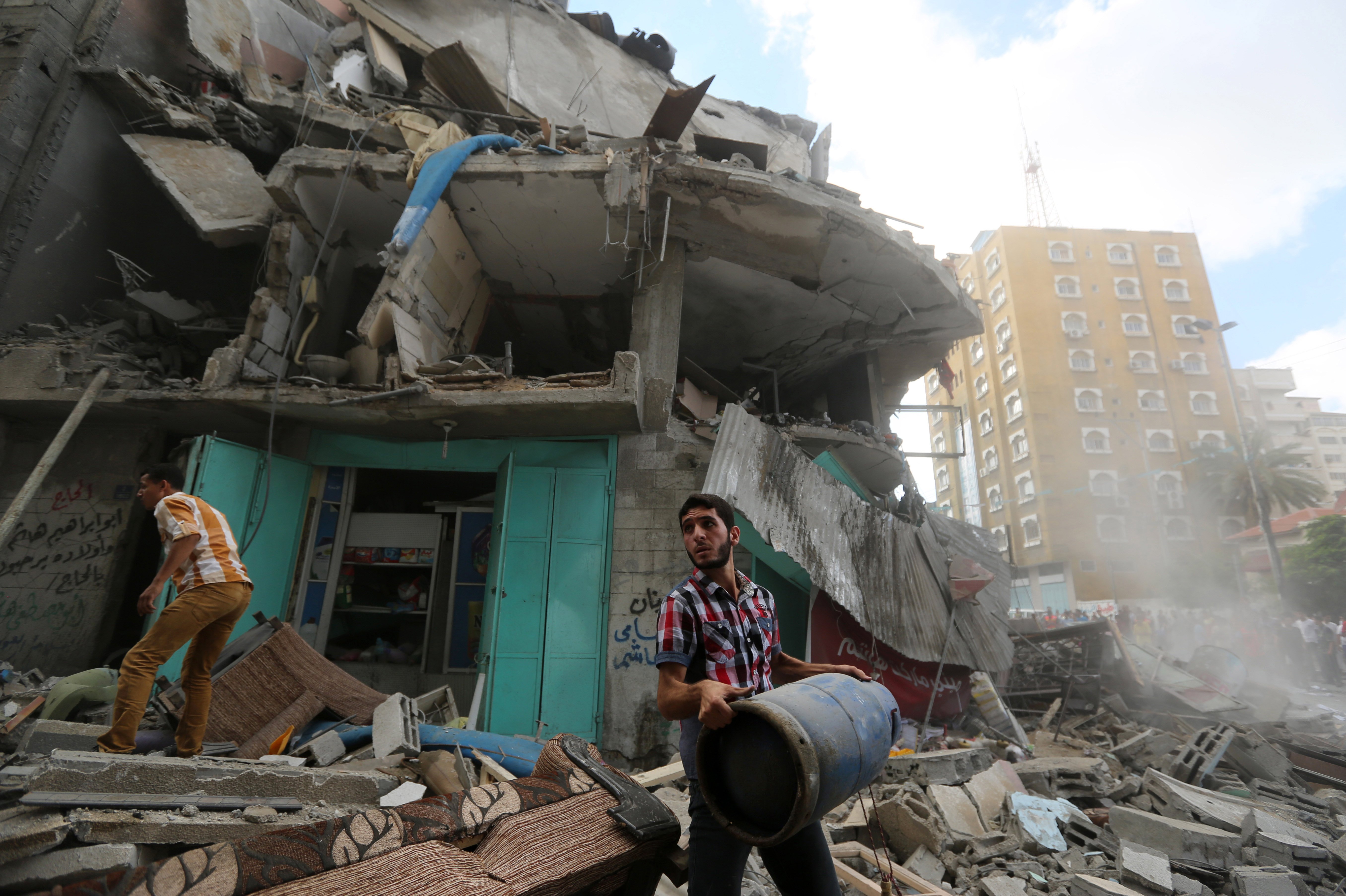 A Palestinian salvages rubble of their destroyed homes after their apartment building was hit by an Israeli missile strike in Gaza City on July 18, 2014.