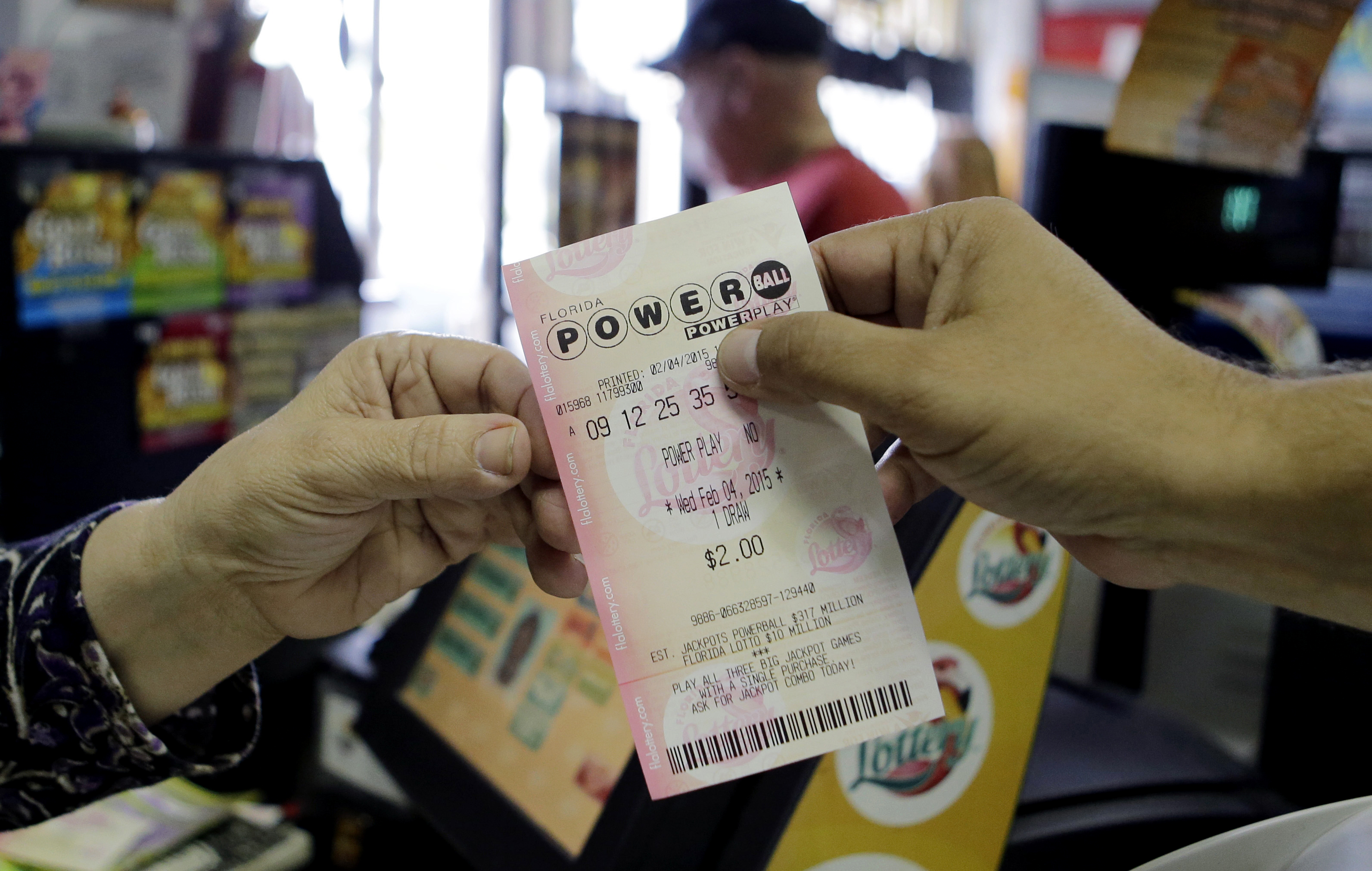 A store clerk hands a customer his Powerball ticket at a local grocery store in Hialeah, Fla., Wednesday, Feb. 4, 2015