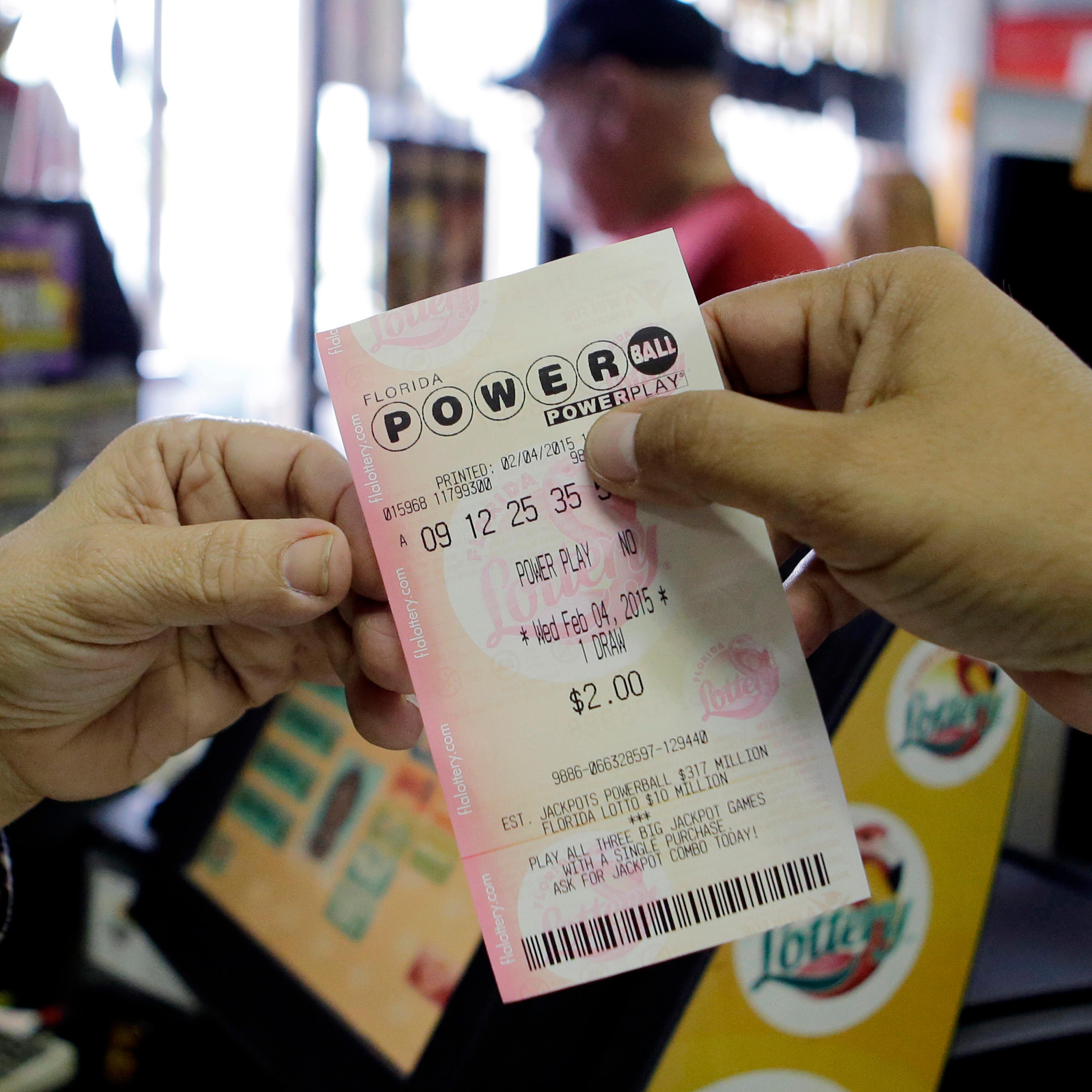 A store clerk hands a customer his Powerball ticket at a local grocery store in Hialeah, Fla., Wednesday, Feb. 4, 2015