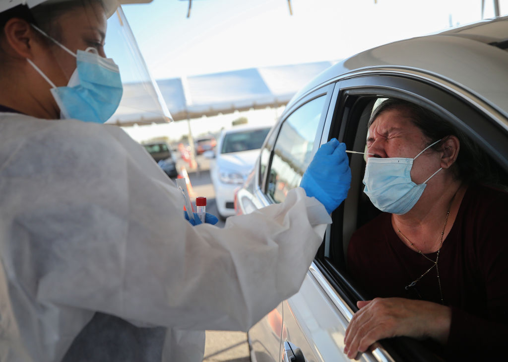 A woman receives a nasal swab test at a drive-in COVID-19 testing site