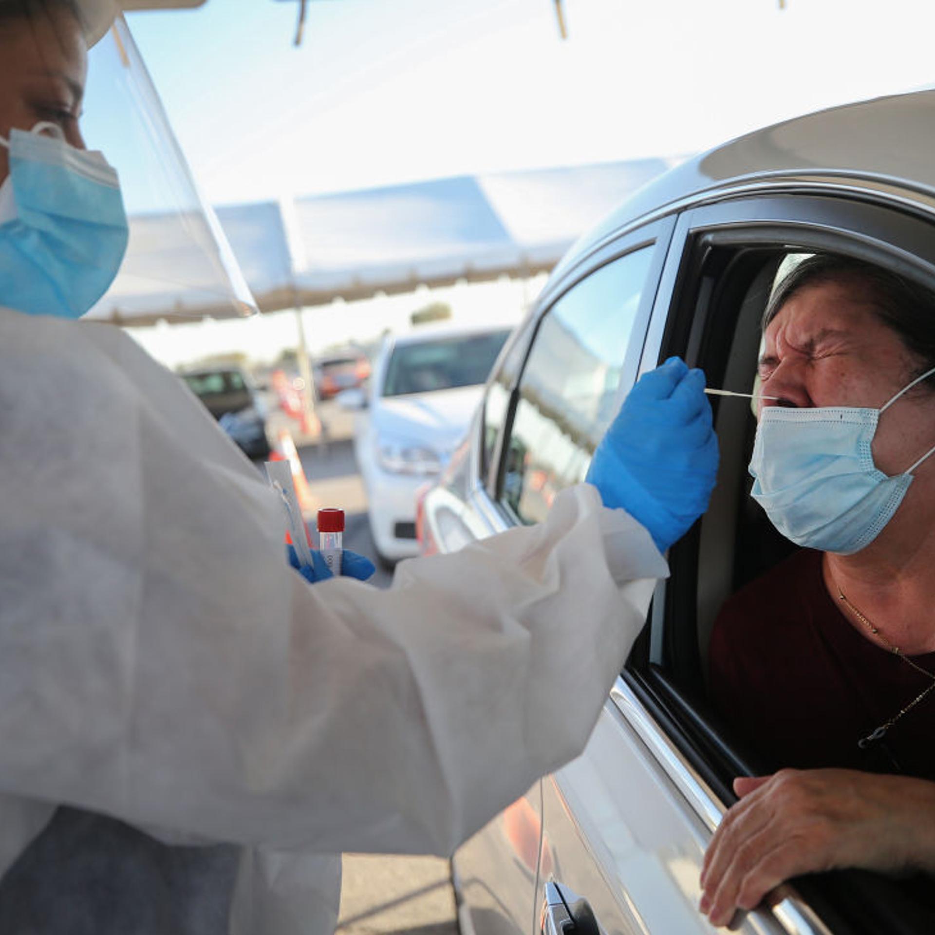 A woman receives a nasal swab test at a drive-in COVID-19 testing site