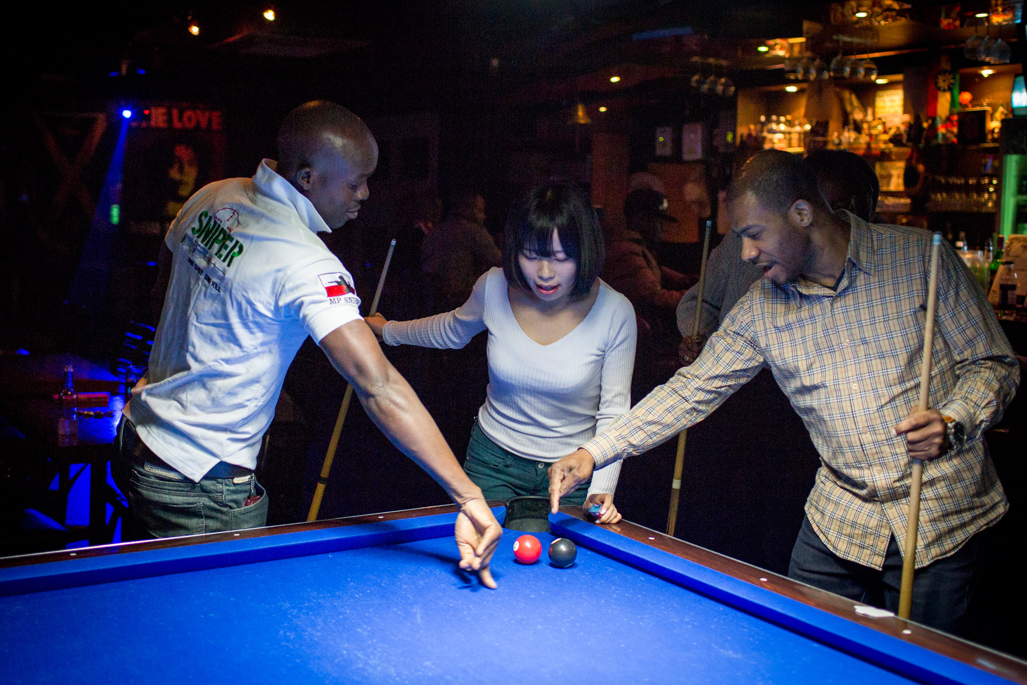 Kyoung-ok plays pool with Christian King of Liberia, left, and Jerry Alexander of Canada, right, at Club Zion, a Jamaican bar, on March 19 in Itaewon, Seoul, South Korea. After not meeting many foreigners as a child, Kyong-ok loves to visit Itaewon, whic