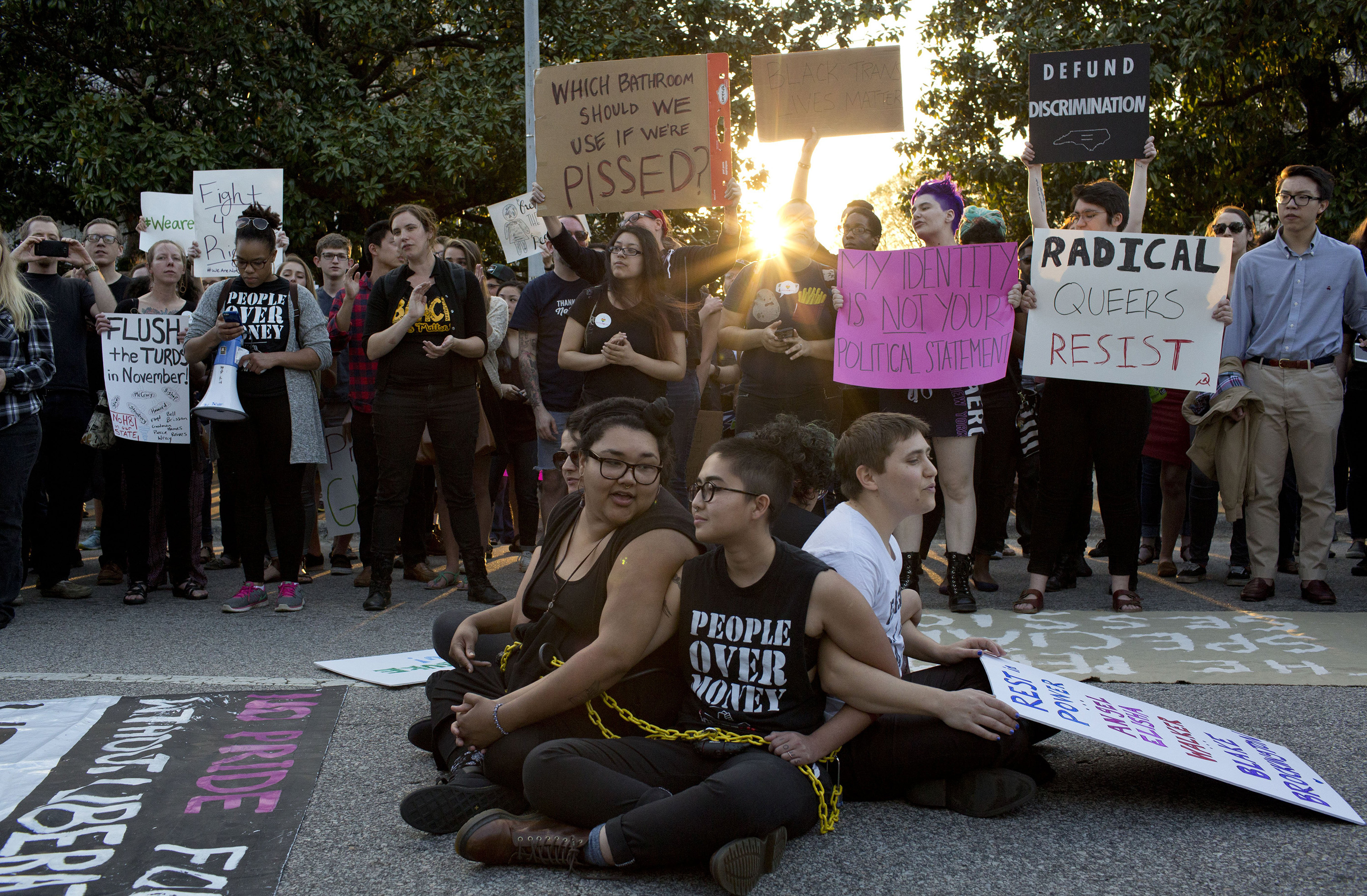 Front from left, demonstrators Jess Jude, Loan Tran and Noah Rubin-Blose, sit chained together in the middle of the street during a protest against House Bill 2 outside of the Governor's Mansion in Raleigh, N.C., on March 24, 2016,.