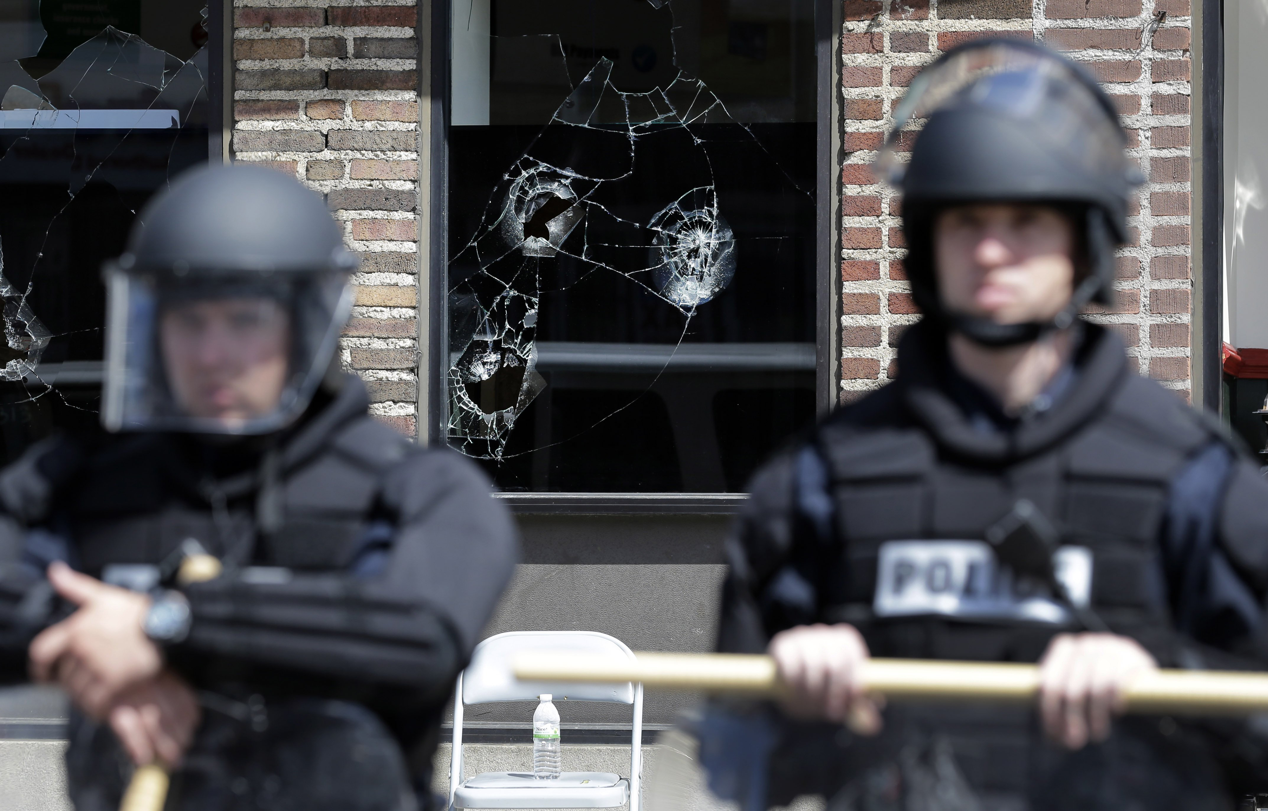 Broken store windows remain as members of the Anne Arundel County Police guard the intersection of North Avenue and Pennsylvania Avenue, on April 29, 2015, in Baltimore.
