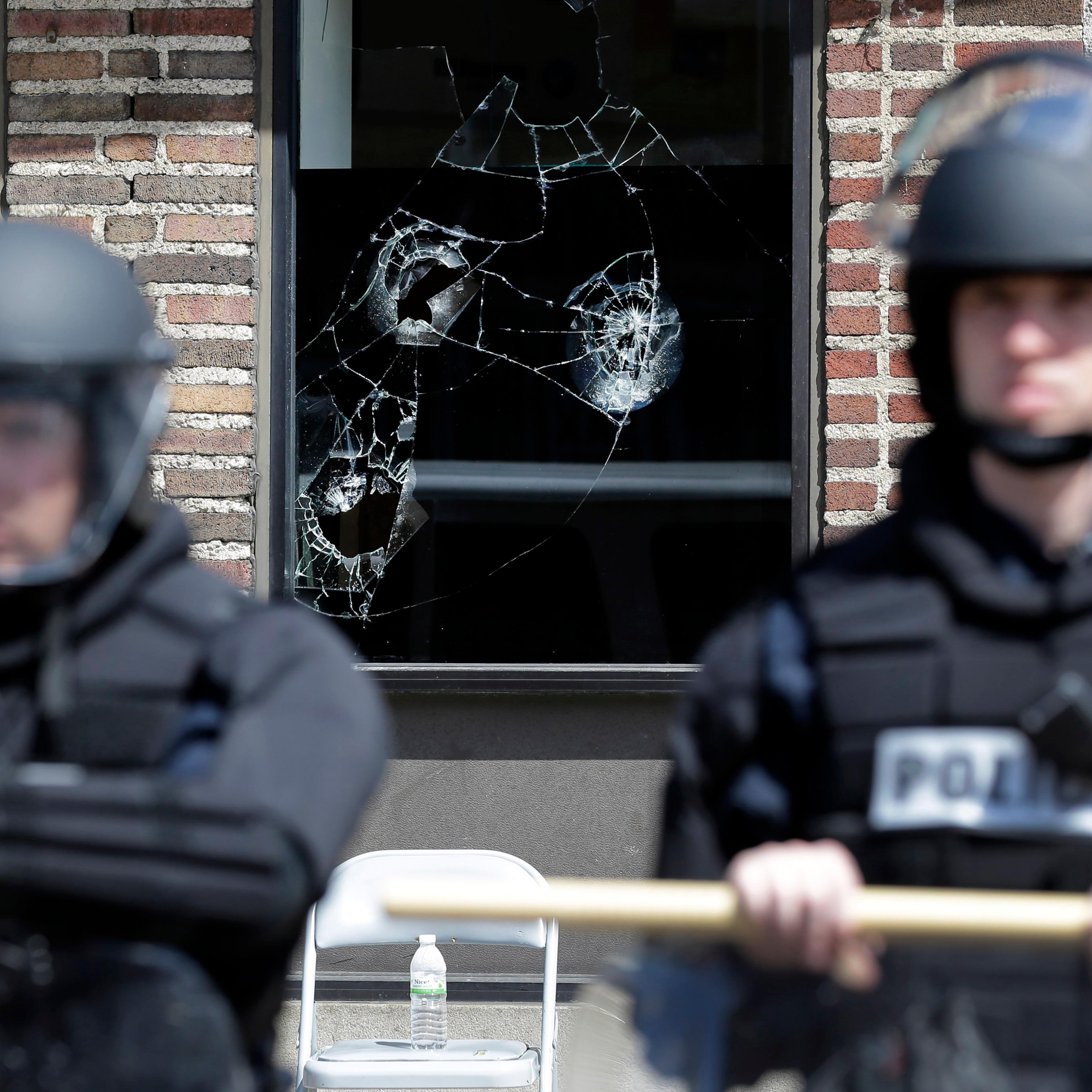 Broken store windows remain as members of the Anne Arundel County Police guard the intersection of North Avenue and Pennsylvania Avenue, on April 29, 2015, in Baltimore.