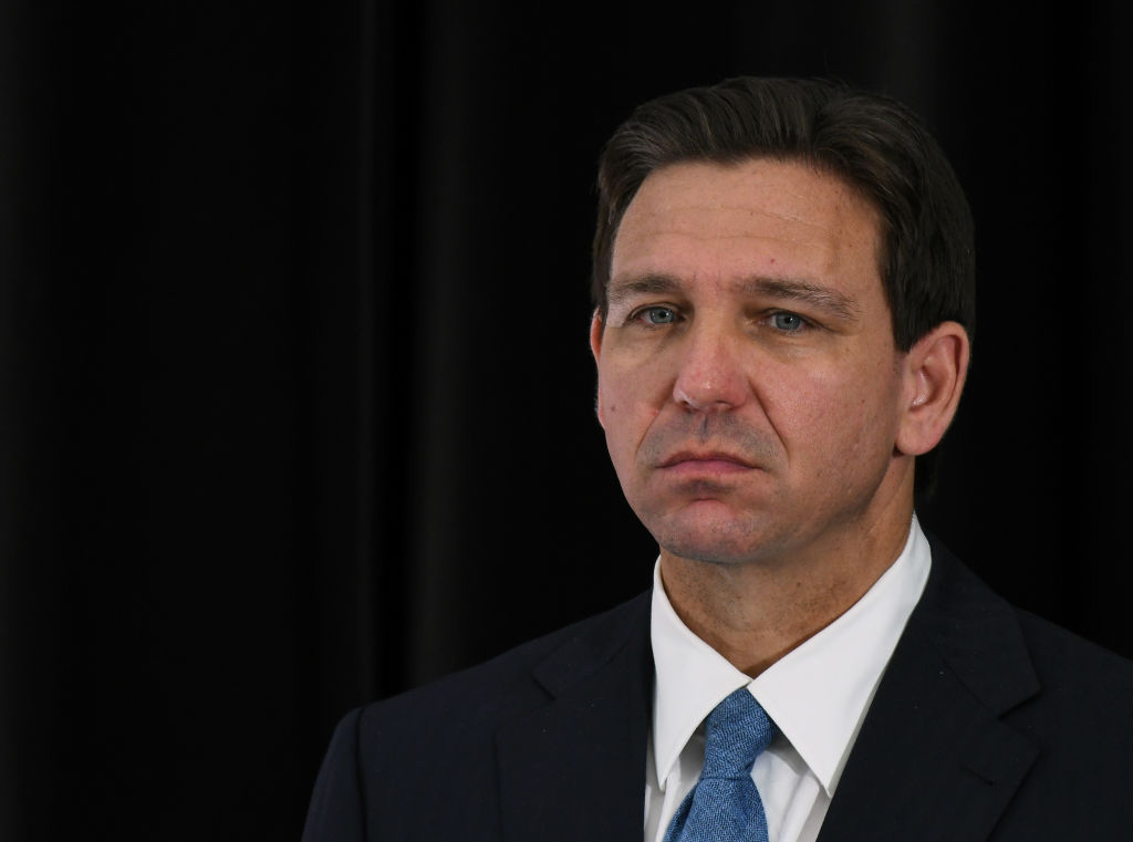 Florida Governor Ron DeSantis listens to a speaker at a
