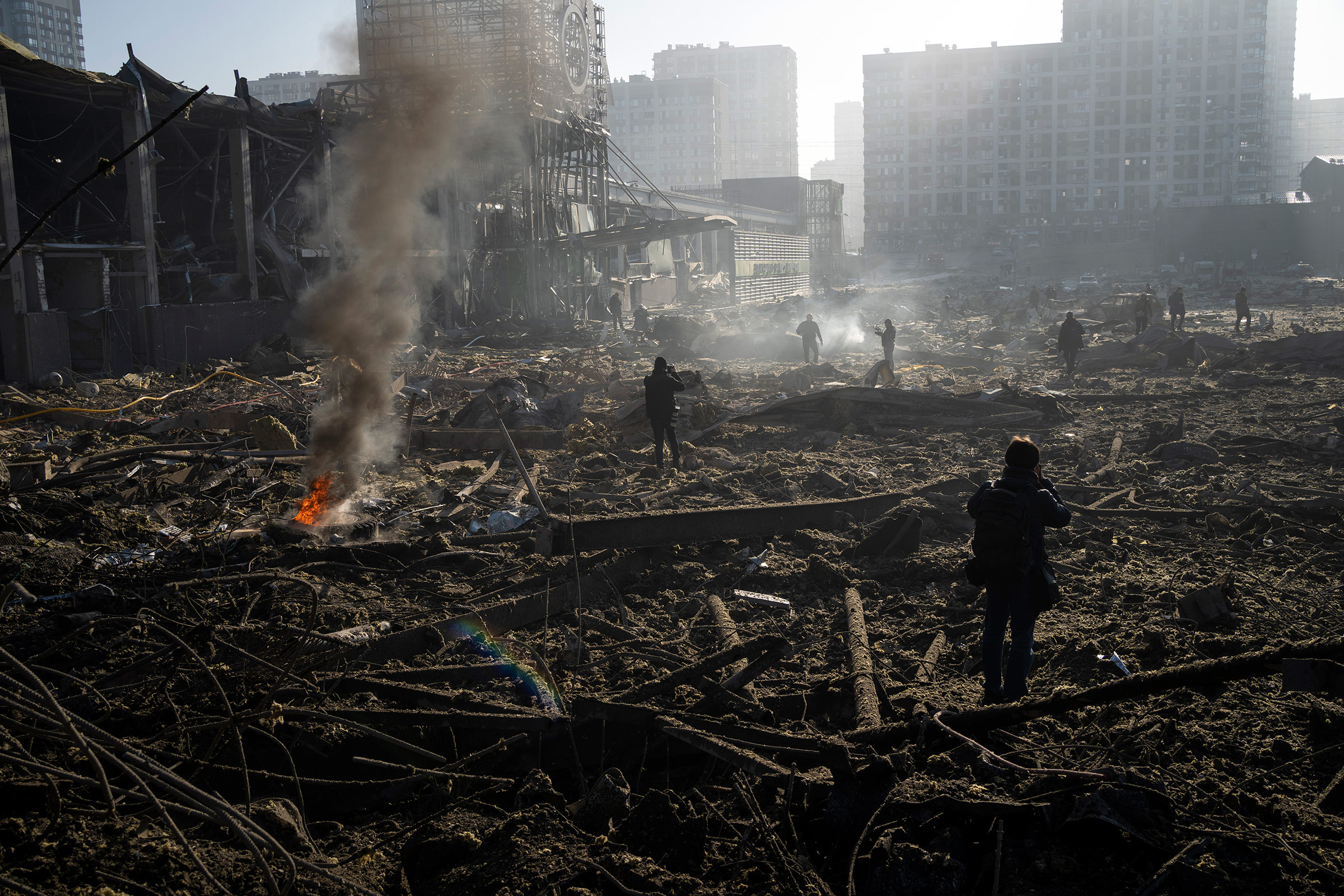 People gather amid the destruction caused after shelling of a shopping center, in Kyiv, Ukraine, March 21, 2022.