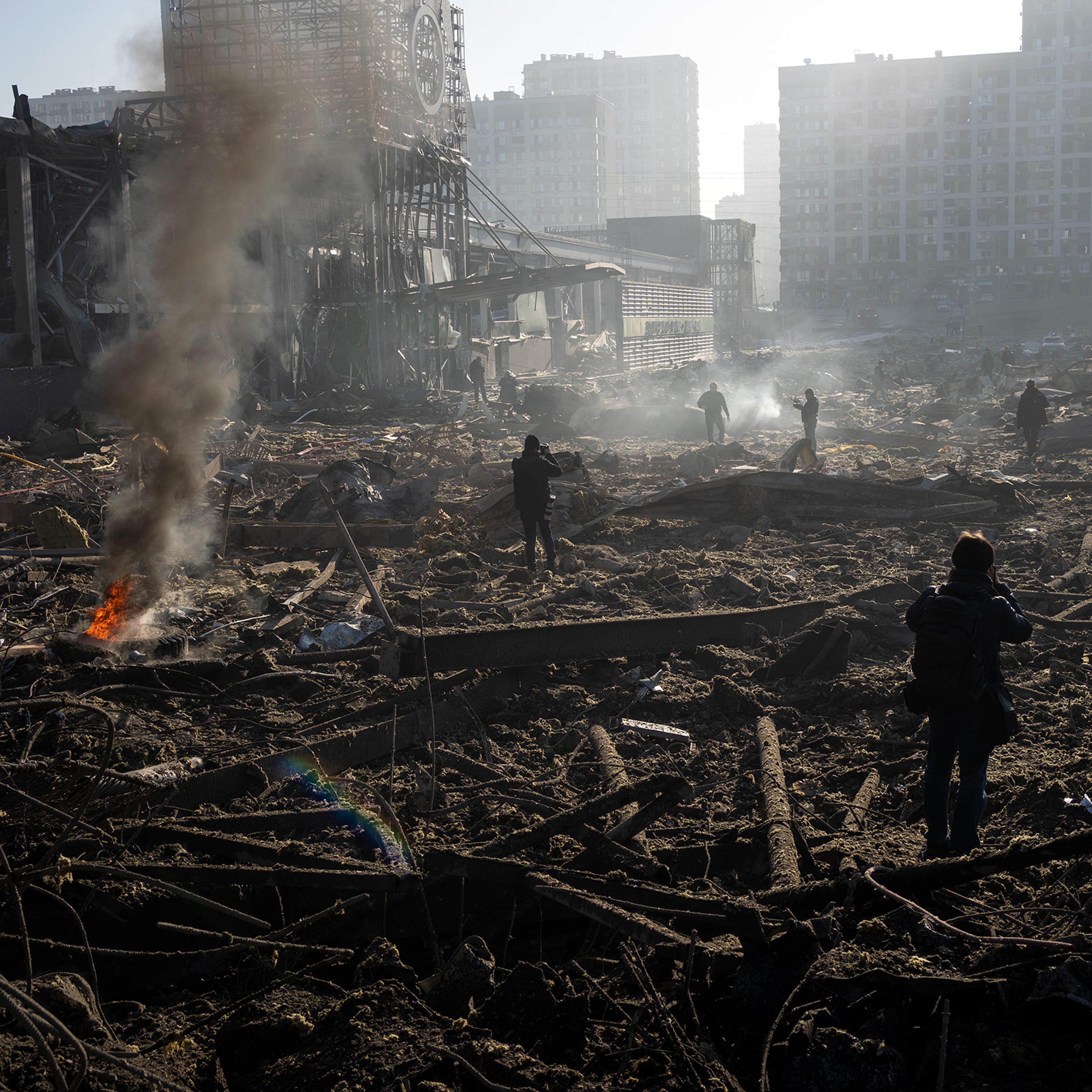 People gather amid the destruction caused after shelling of a shopping center, in Kyiv, Ukraine, March 21, 2022.
