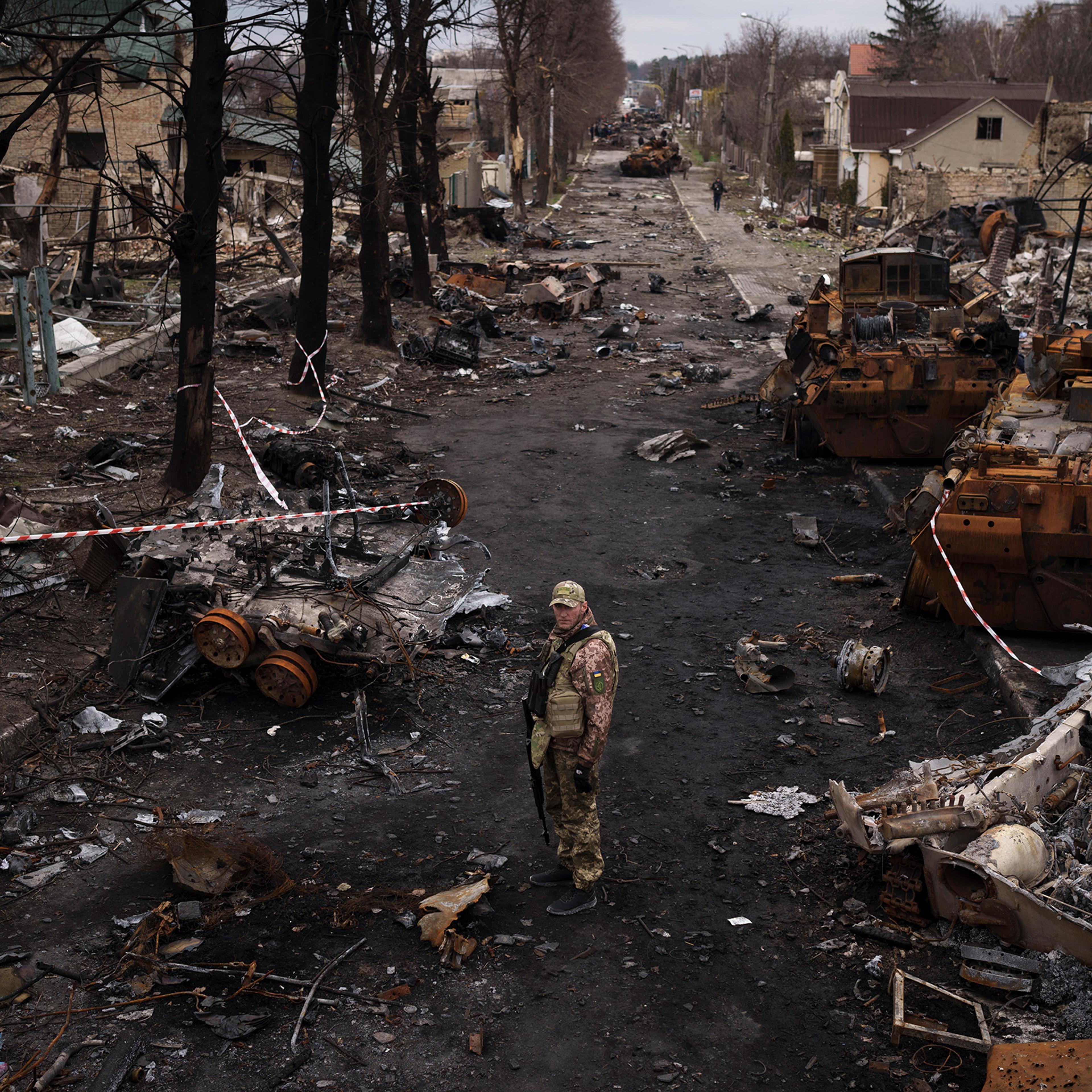 A Ukrainian serviceman stands amid destroyed Russian tanks in Bucha, on the outskirts of Kyiv, on April 6