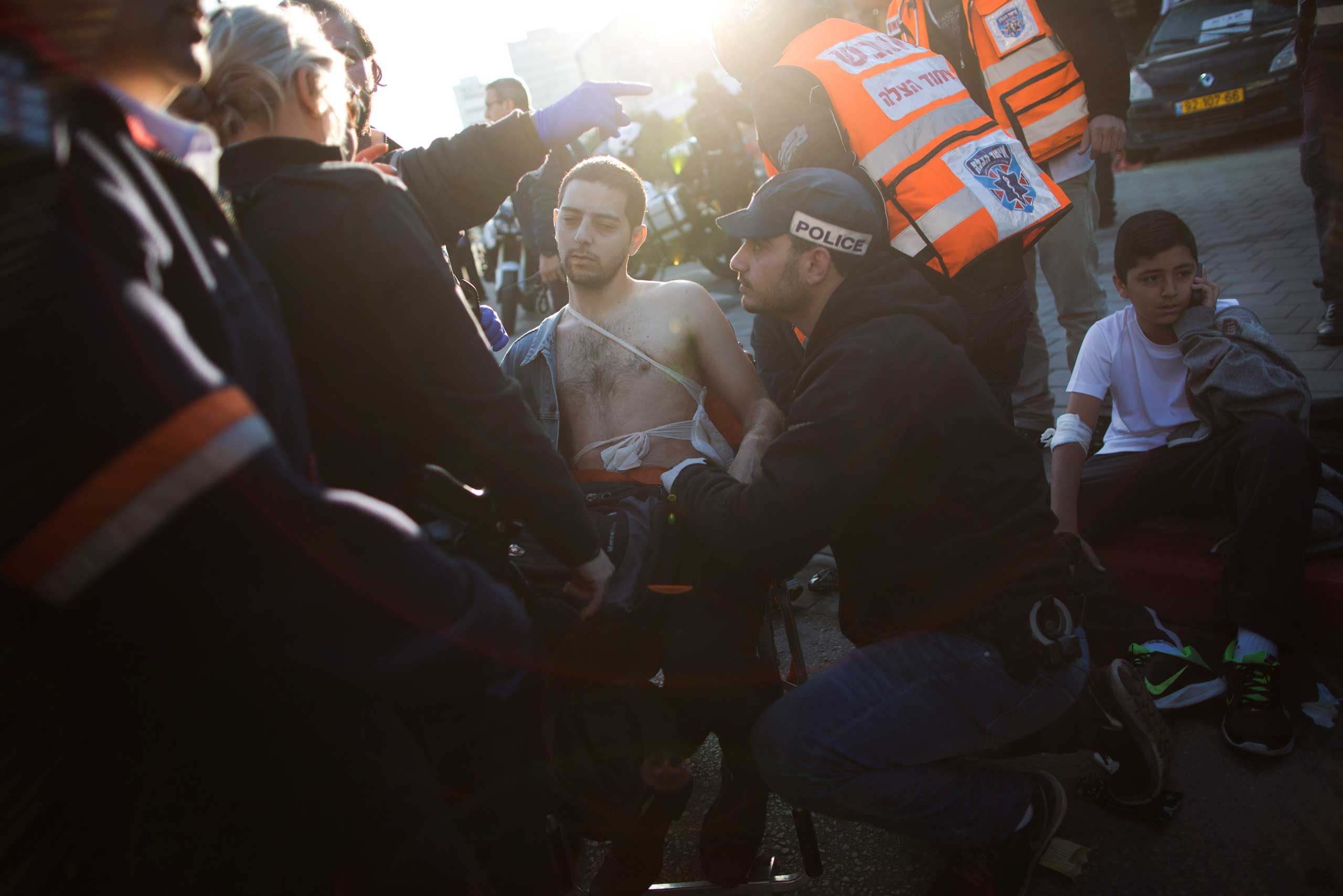 An Israeli police officer and paramedics treat an injured man at the scene of a stabbing in Tel Aviv, Jan. 21, 2015.