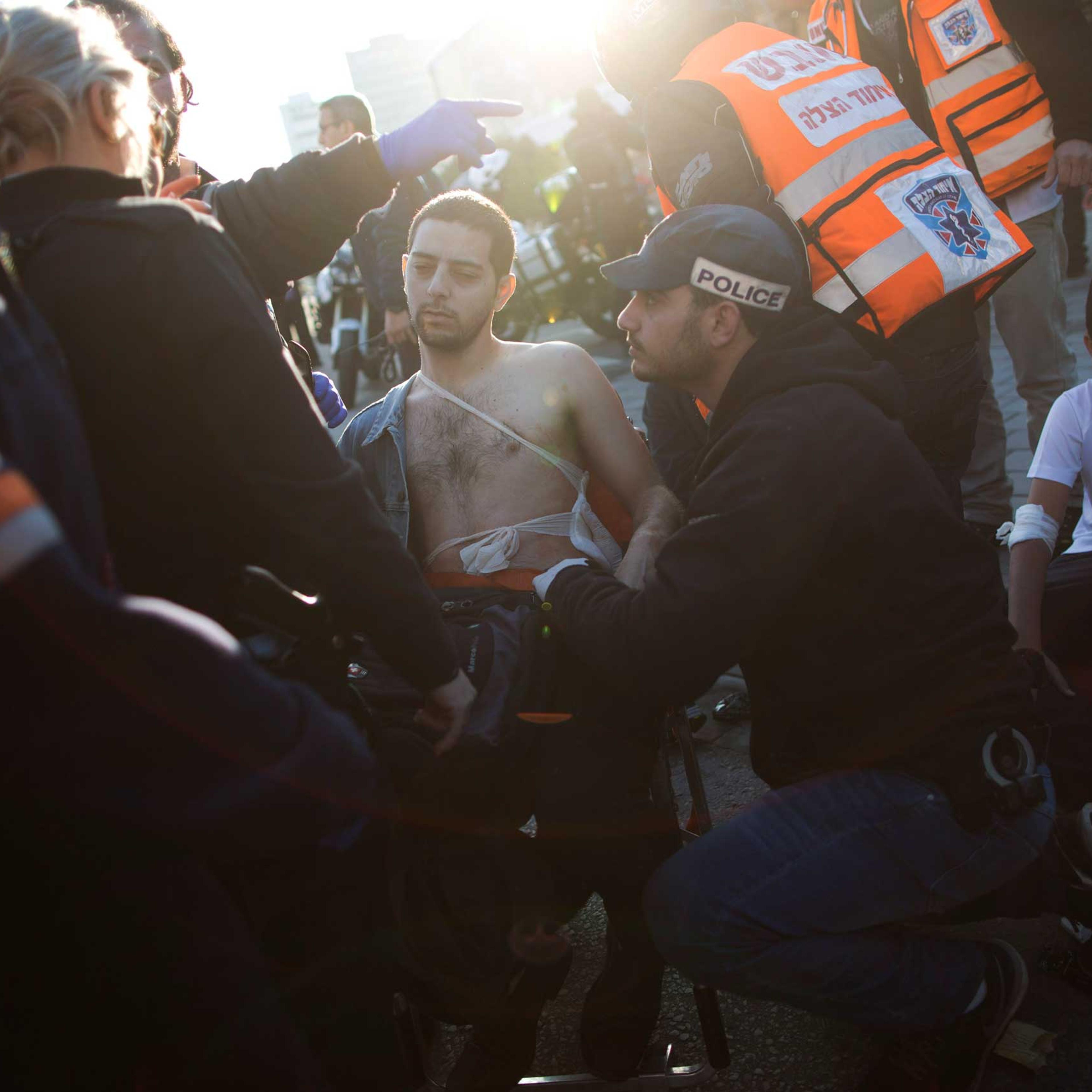 An Israeli police officer and paramedics treat an injured man at the scene of a stabbing in Tel Aviv, Jan. 21, 2015.