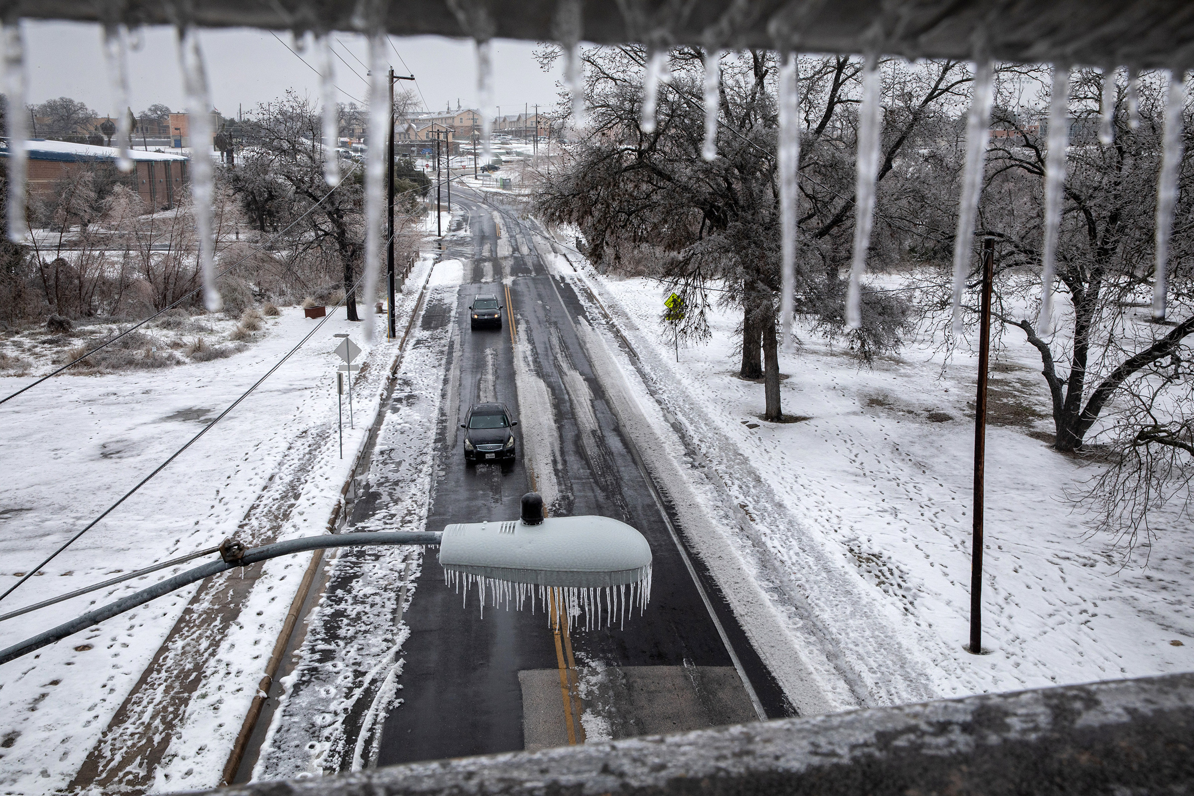 Ice and snow cover an area as seen through an overpass railing in Austin, Texas., on Feb. 17