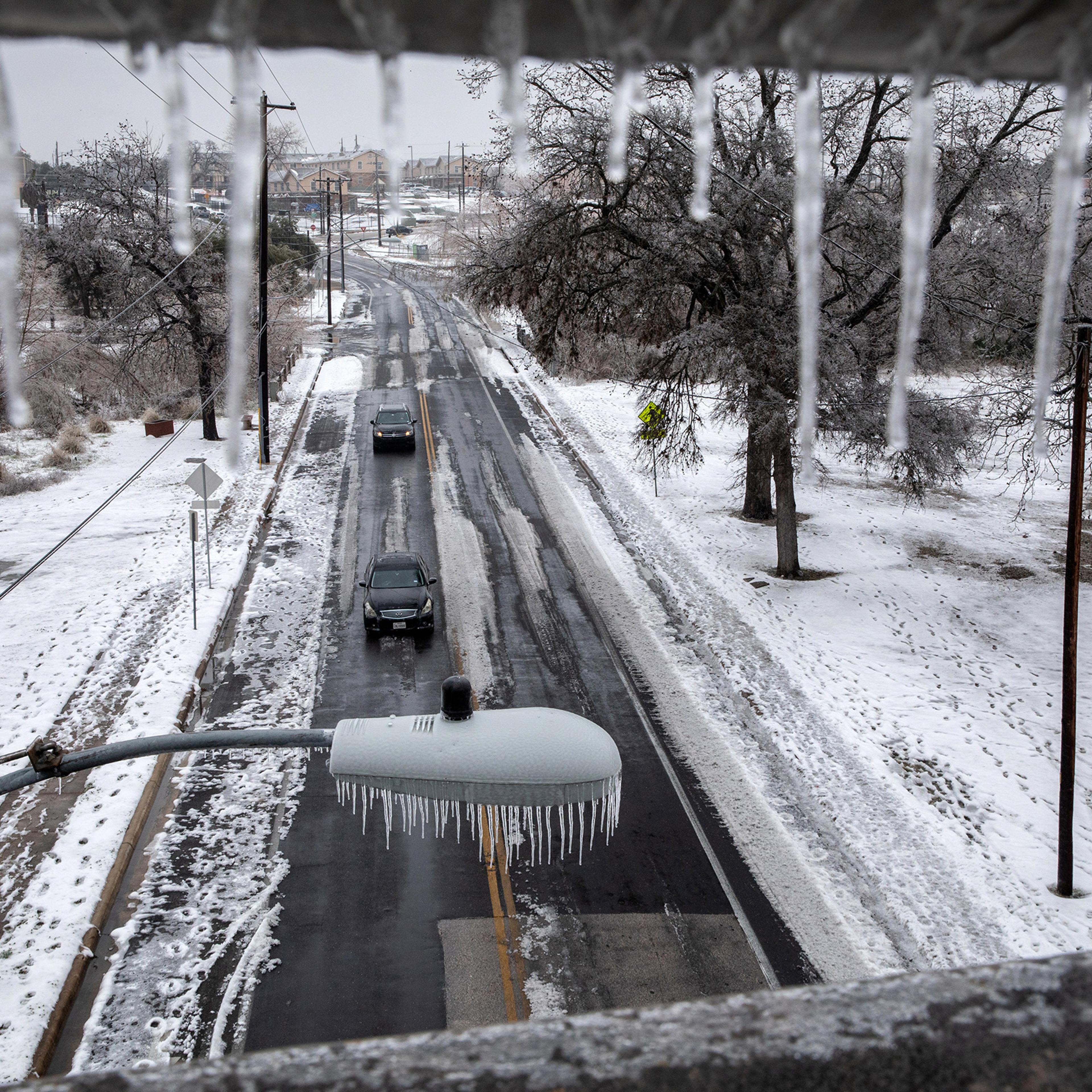 Ice and snow cover an area as seen through an overpass railing in Austin, Texas., on Feb. 17