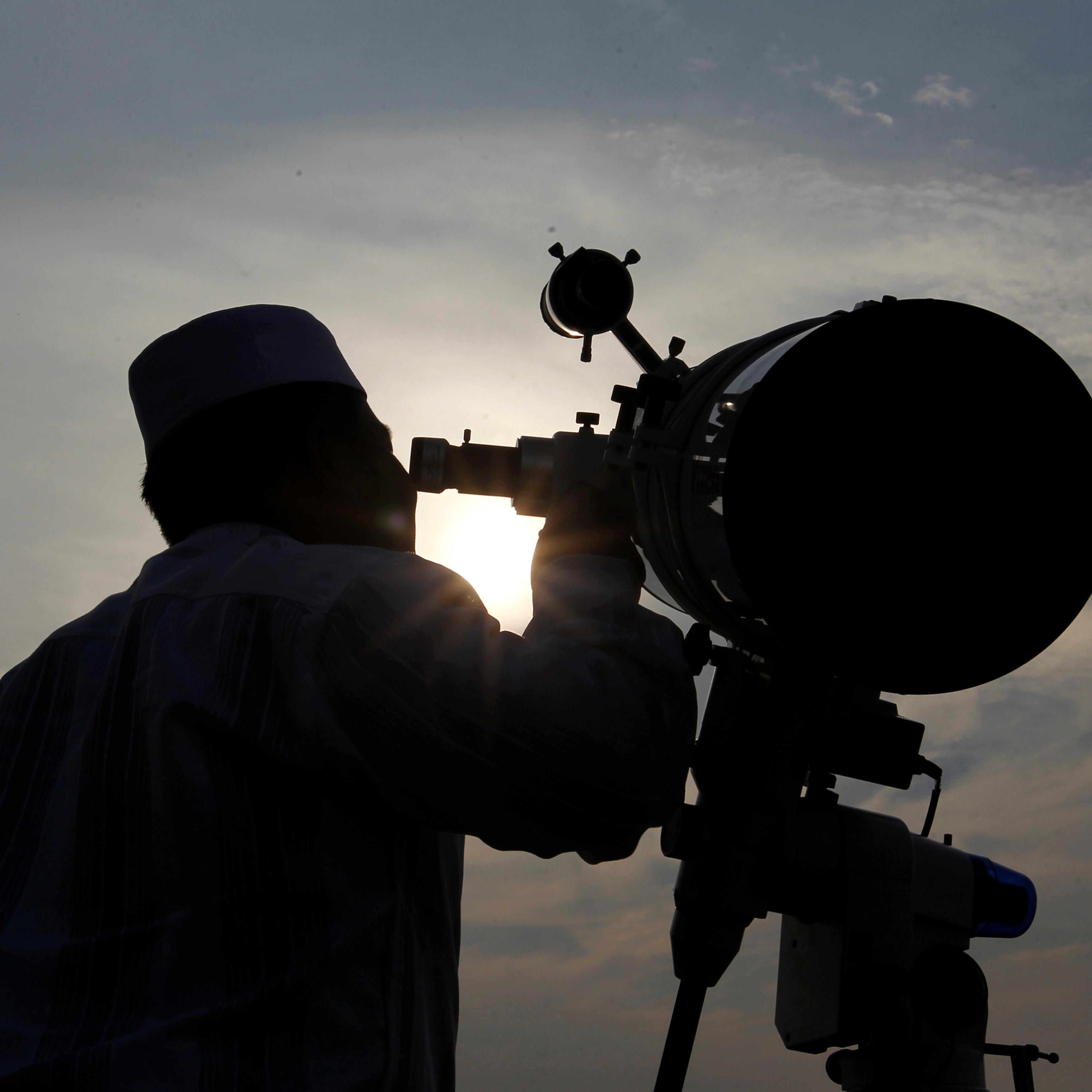 A Muslim man uses a telescope to observe the moon before the Muslim holy month of Ramadan