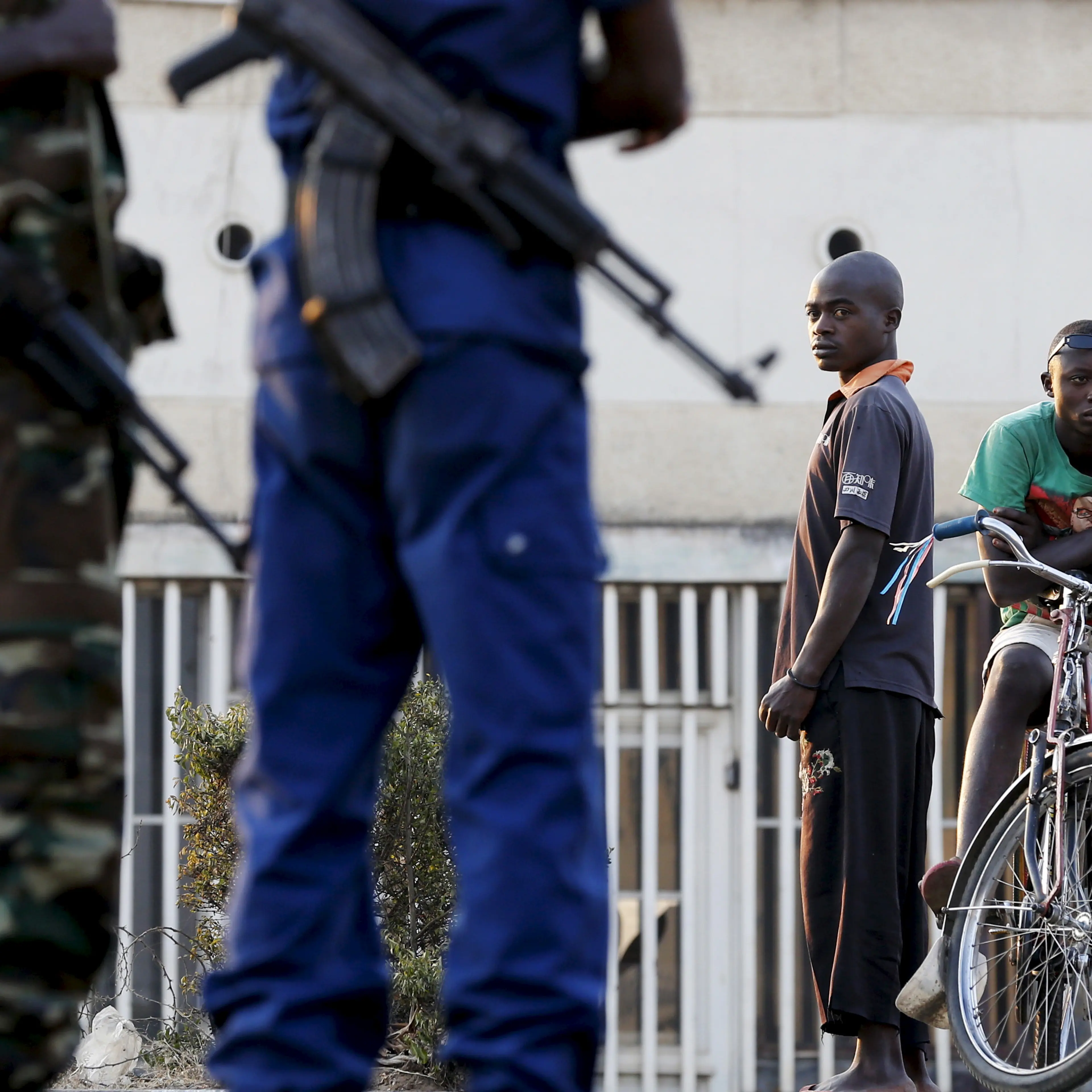 Residents look on as police and soldiers guard a voting station in Burundi's capital Bujumbura during the country's presidential election